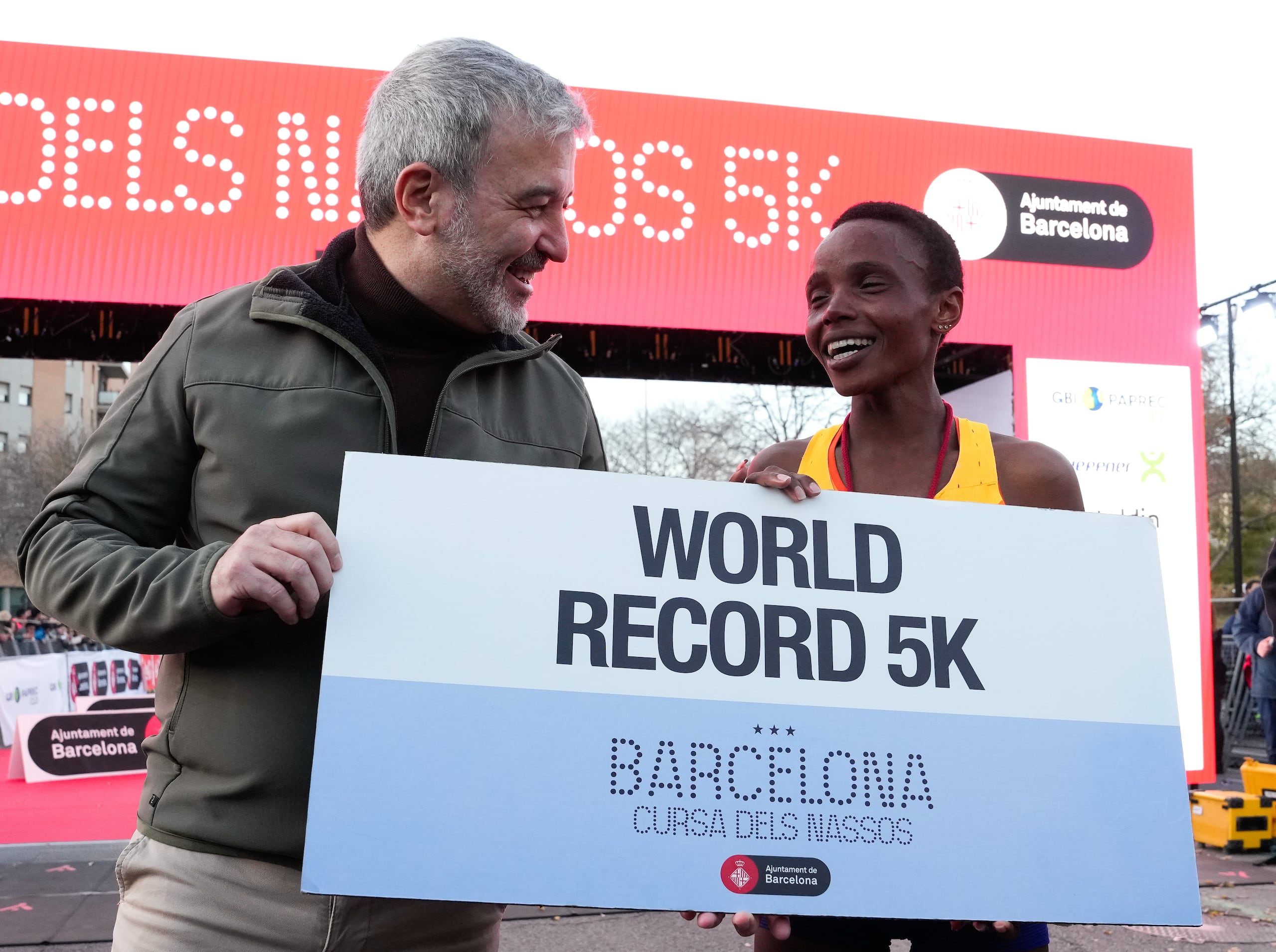La keniana Beatice Chebet recibe del alcalde de Barcelona, Jaume Collboni, la prueba de que batió la marca mundial de 5 kilómetros sobre carretera este domingo en la ciudad española.