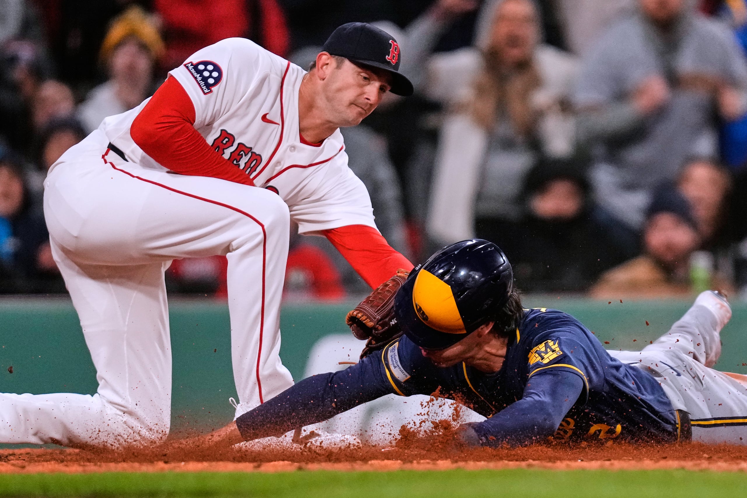 Christian Yelich, de los Brewers (derecha), anota una carrera tras un sencillo de Garrett Mitchell, mientras que el lanzador de los Red Sox, Garrett Whitlock (izquierda), lo toca.