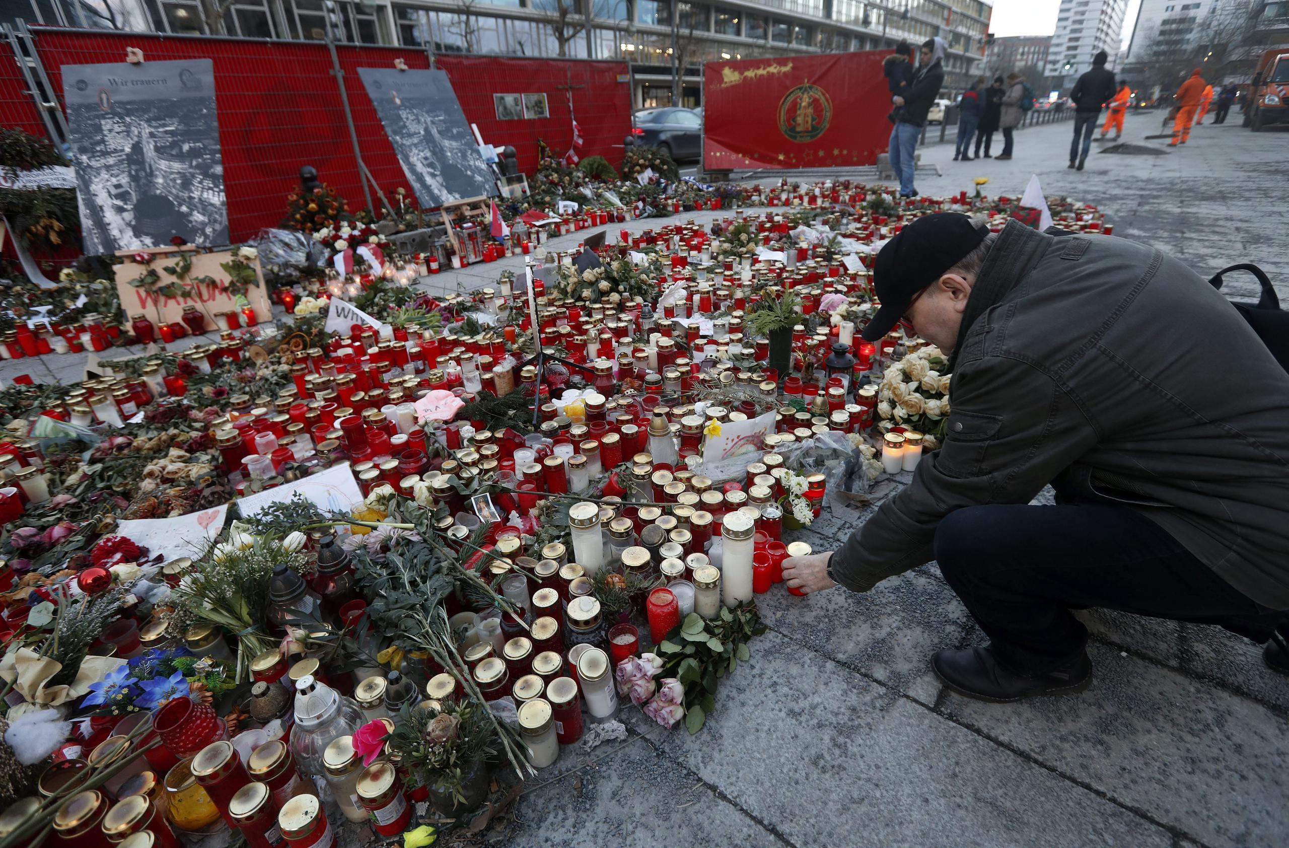 Un hombre pone una vela en un sitio conmemorativo de las víctimas del ataque terrorista con camión en Berlín el 19 de enero de 2017. EFE/EPA/FELIPE TRUBA
