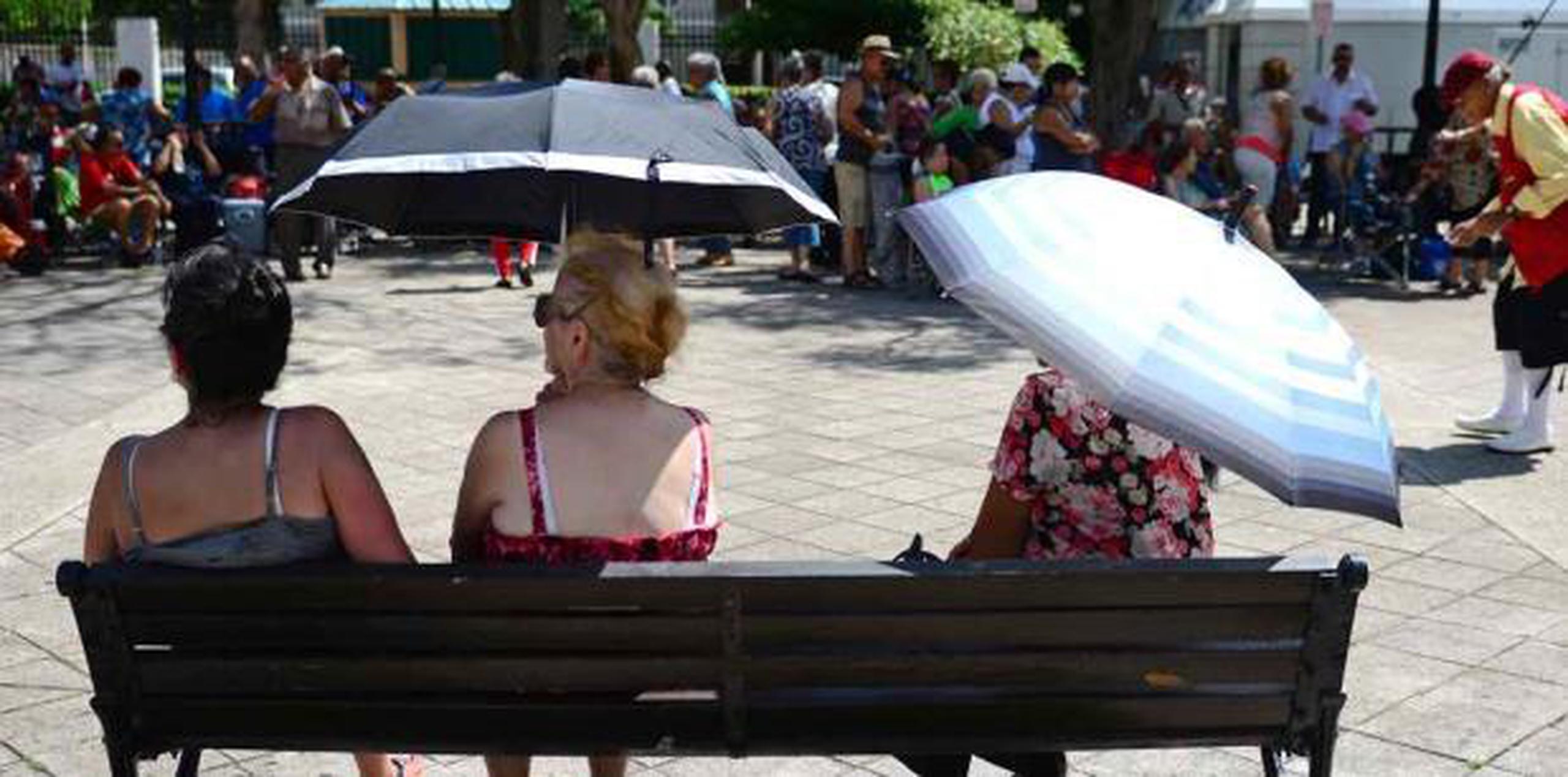 Varias mujeres se escudan del sol con una sombrilla. (Archivo)