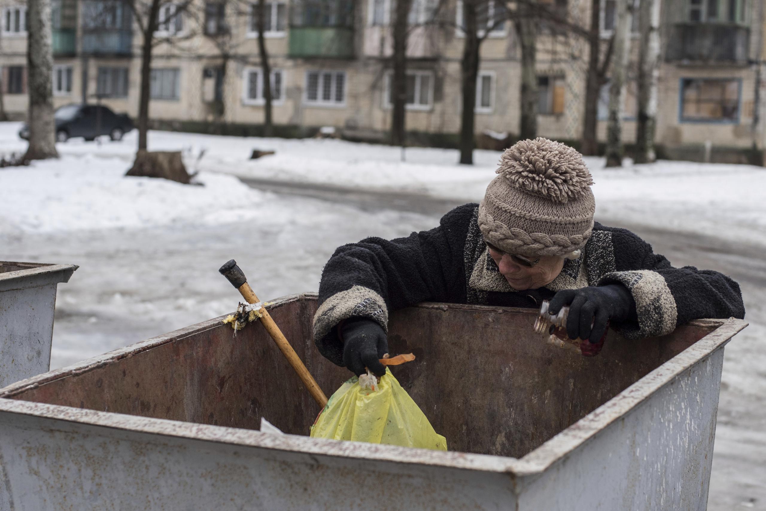 Una mujer busca comida en un contenedor de basura en Avdiivka, Ucrania.