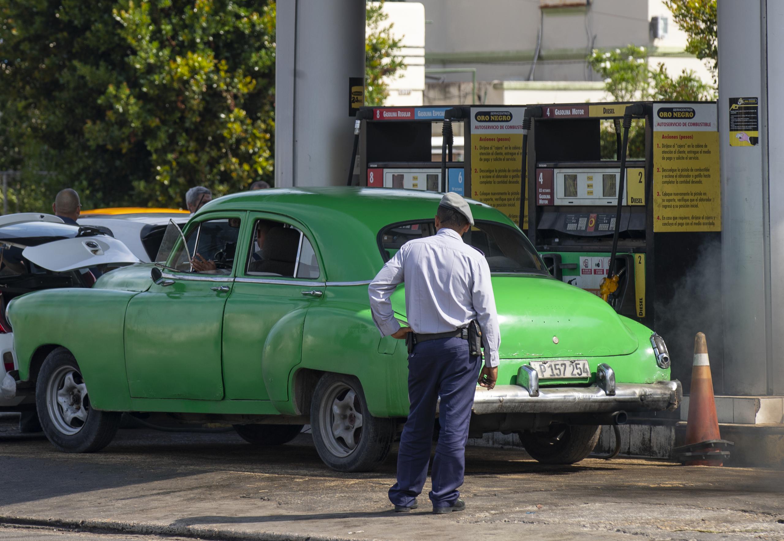 Un policía observa a un coche antiguo en una gasolinera, hoy en La Habana, en Cuba. (EFE/Yander Zamora)