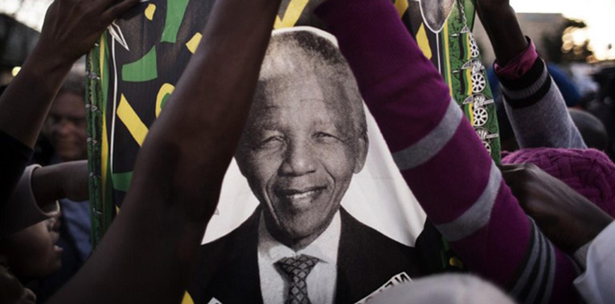 Seguidores de Nelson Mandela ondean una bandera con su imagen a las afueras de la clínica donde se encuentra internado. (AFP)