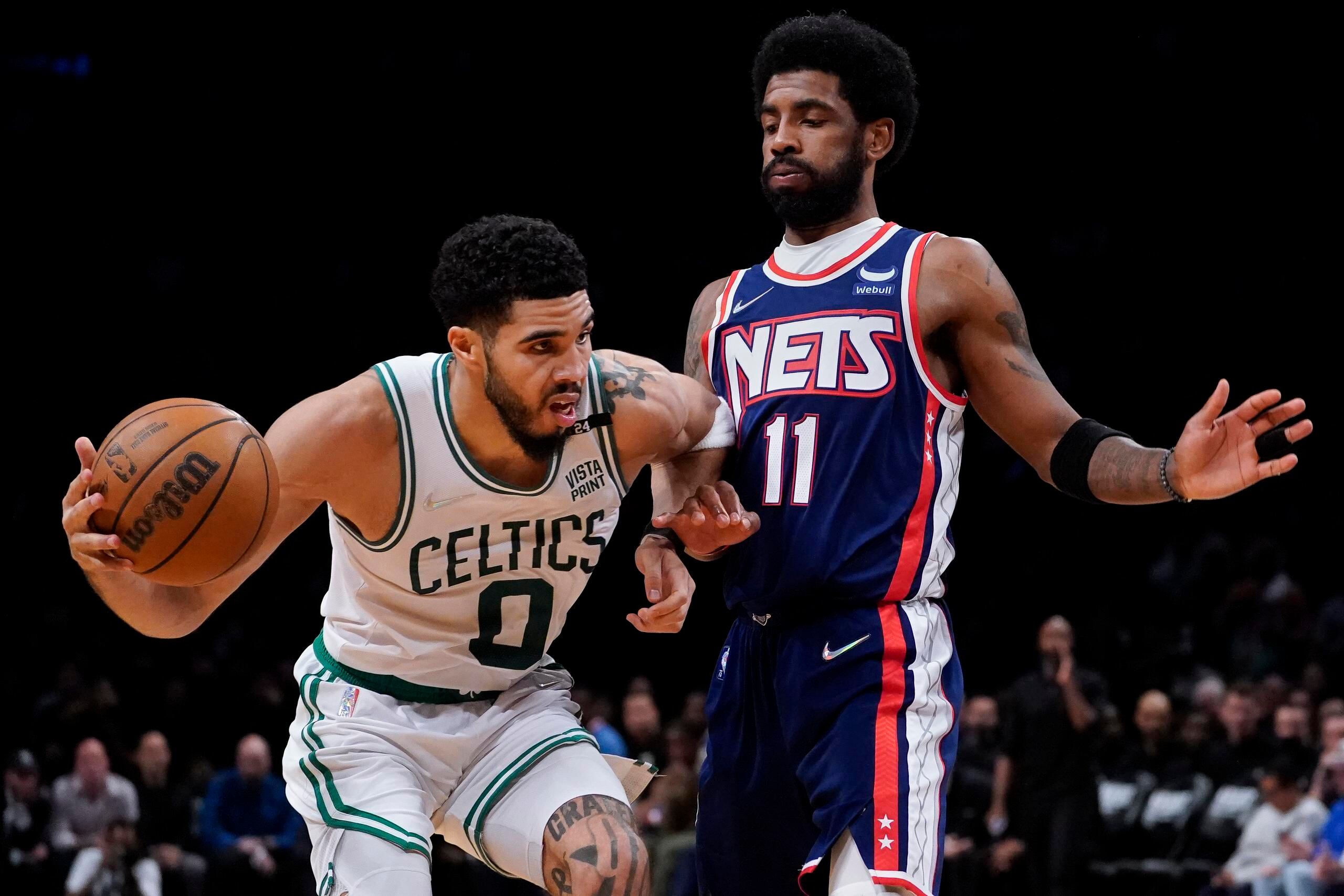El alero de los Celtics de Boston, Jayson Tatum, es defendido por el base de los Nets de Brooklyn Kyrie Irving.