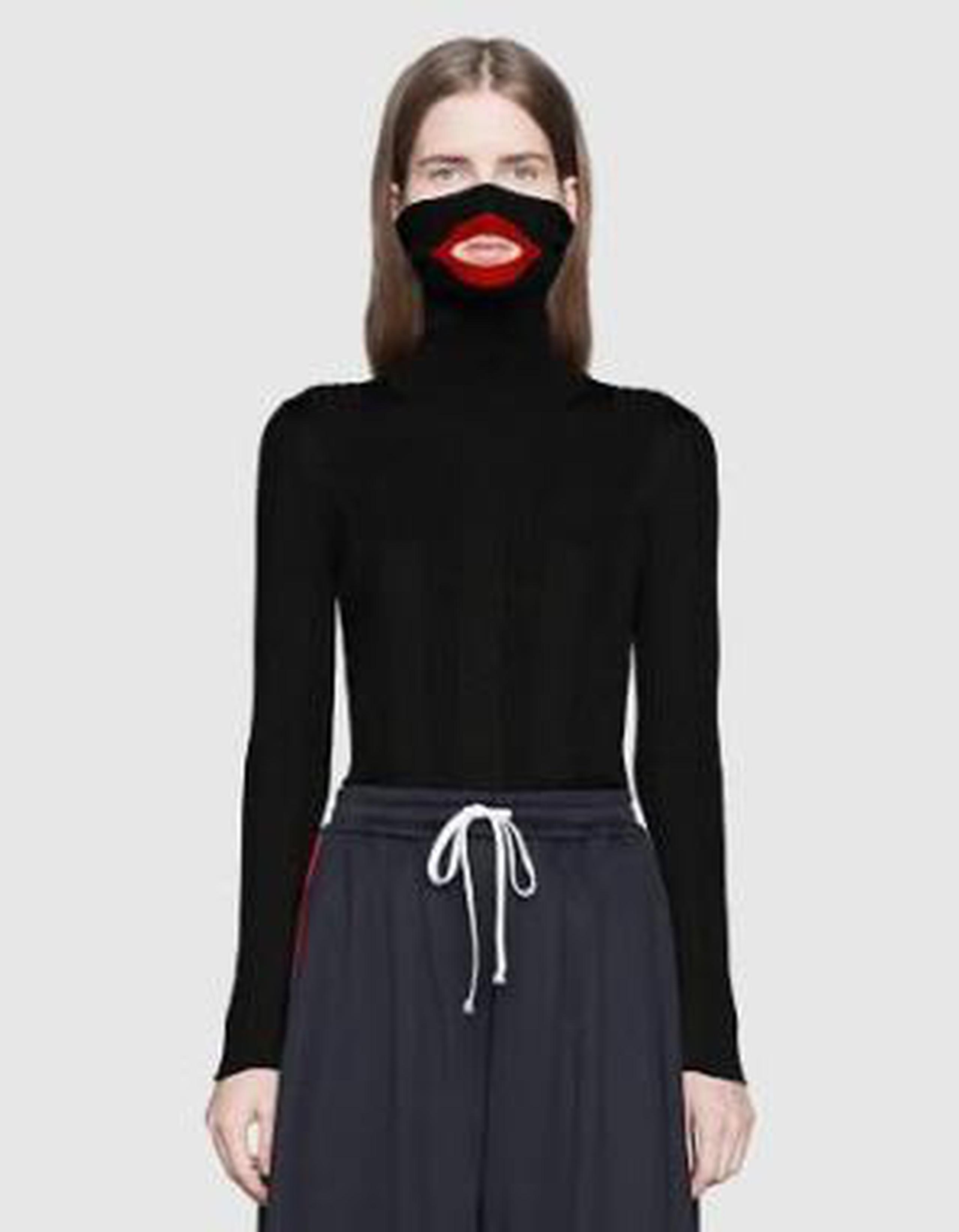 El suéter con cuello extralargo de lana negra cubre la nariz e incluye un recorte bordeado de rojo para la boca. (Gucci)