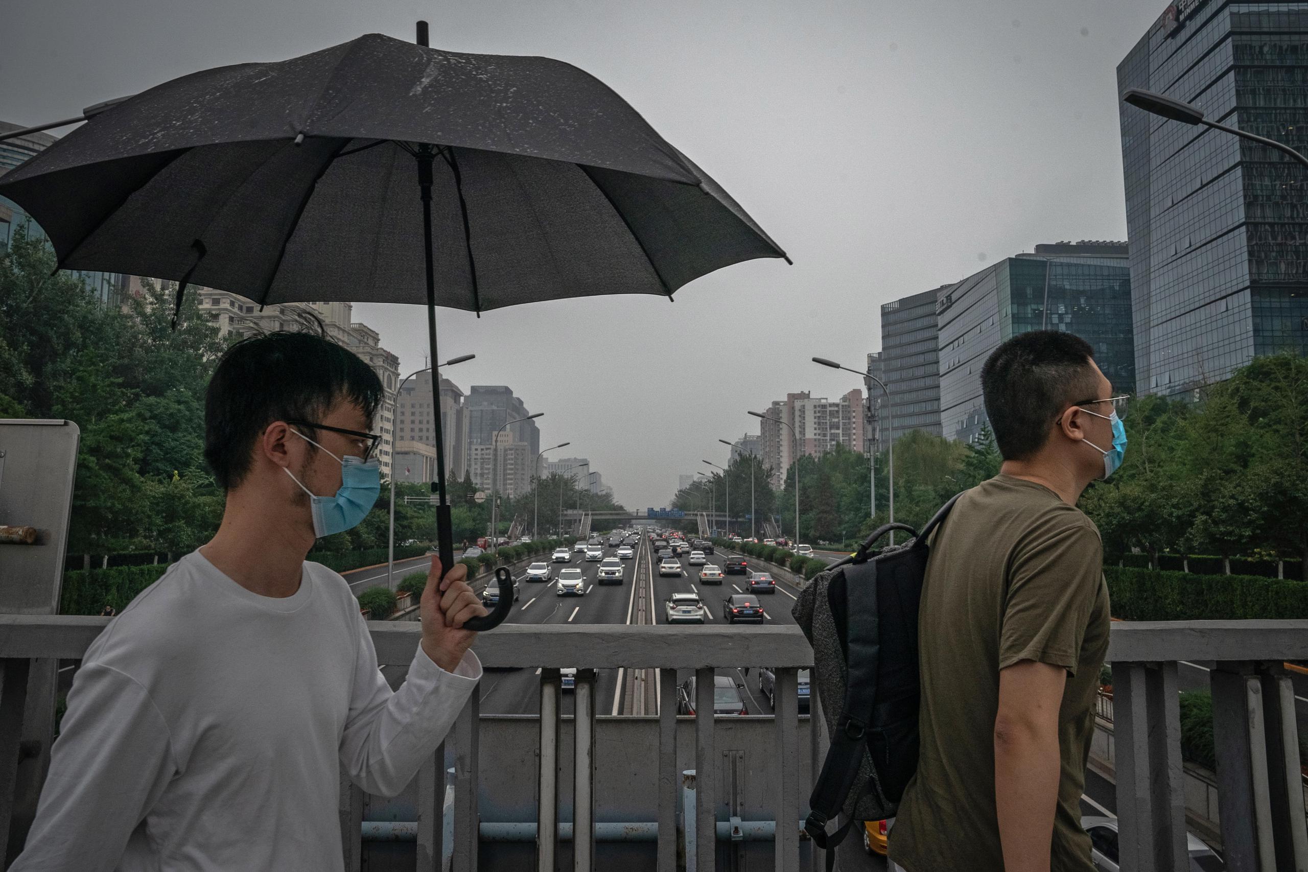 Un hombre camina con sombrilla en China, país azotado por fuertes lluvias en algunas regiones.