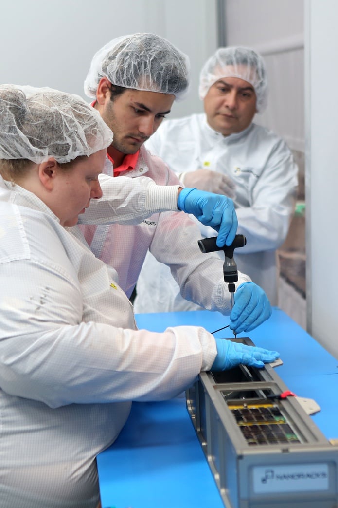 Nanorax Mission Manager Jack Cornish and Julia Wolfenberger work on a container carrying the Puerto Rican satellite PR-CuNaR2.  Take a look at the background of Dr. Amilcar Rinkan Charries, Professor of School of Engineering at the Boyman Campus of the American-American University of Puerto Rico.