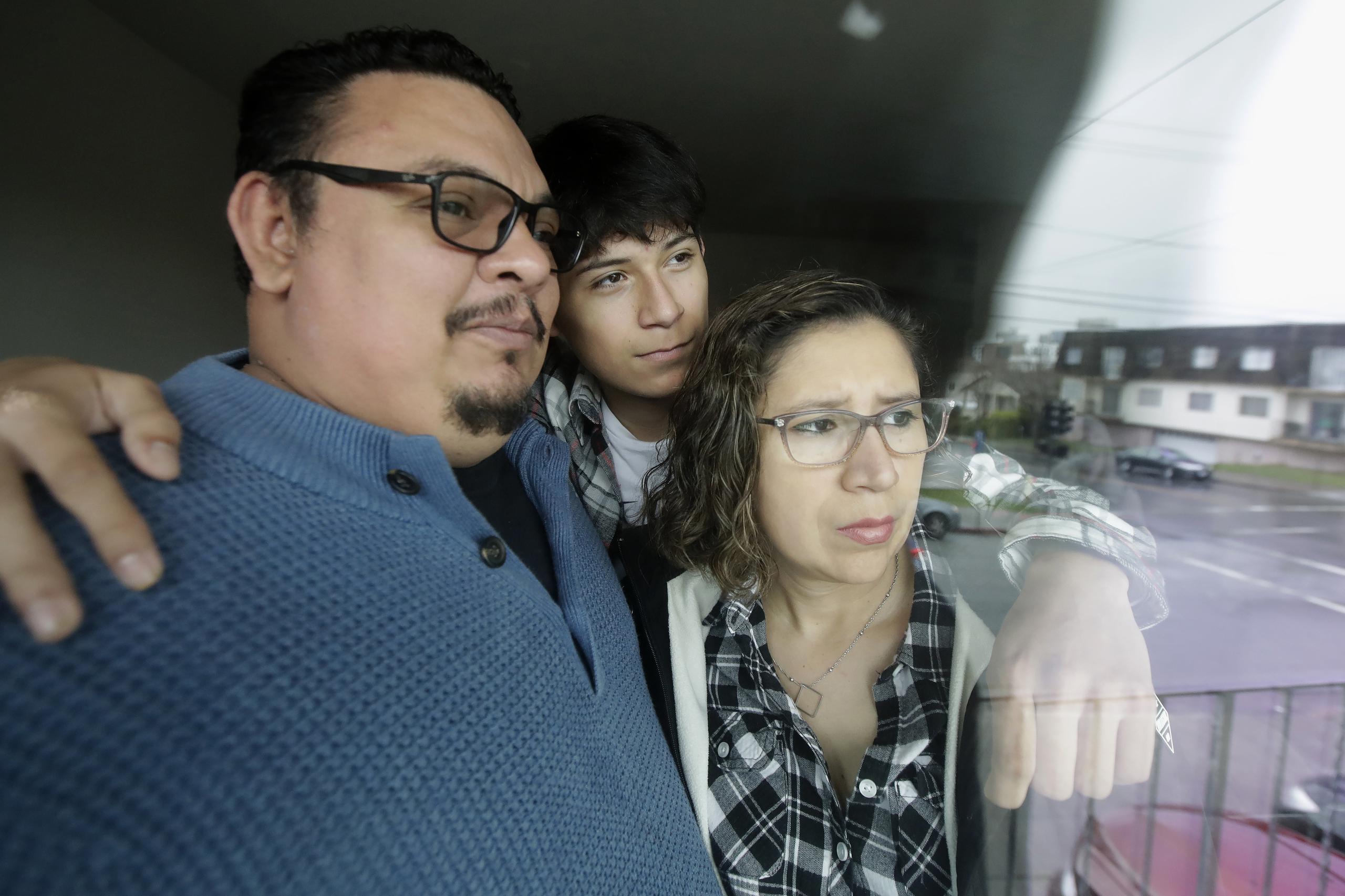 William Gonzalez, su hijo Ricardo, de 14 años, y su esposa Sonia Bautista, junto a una ventana de su apartamento en South San Francisco, California.