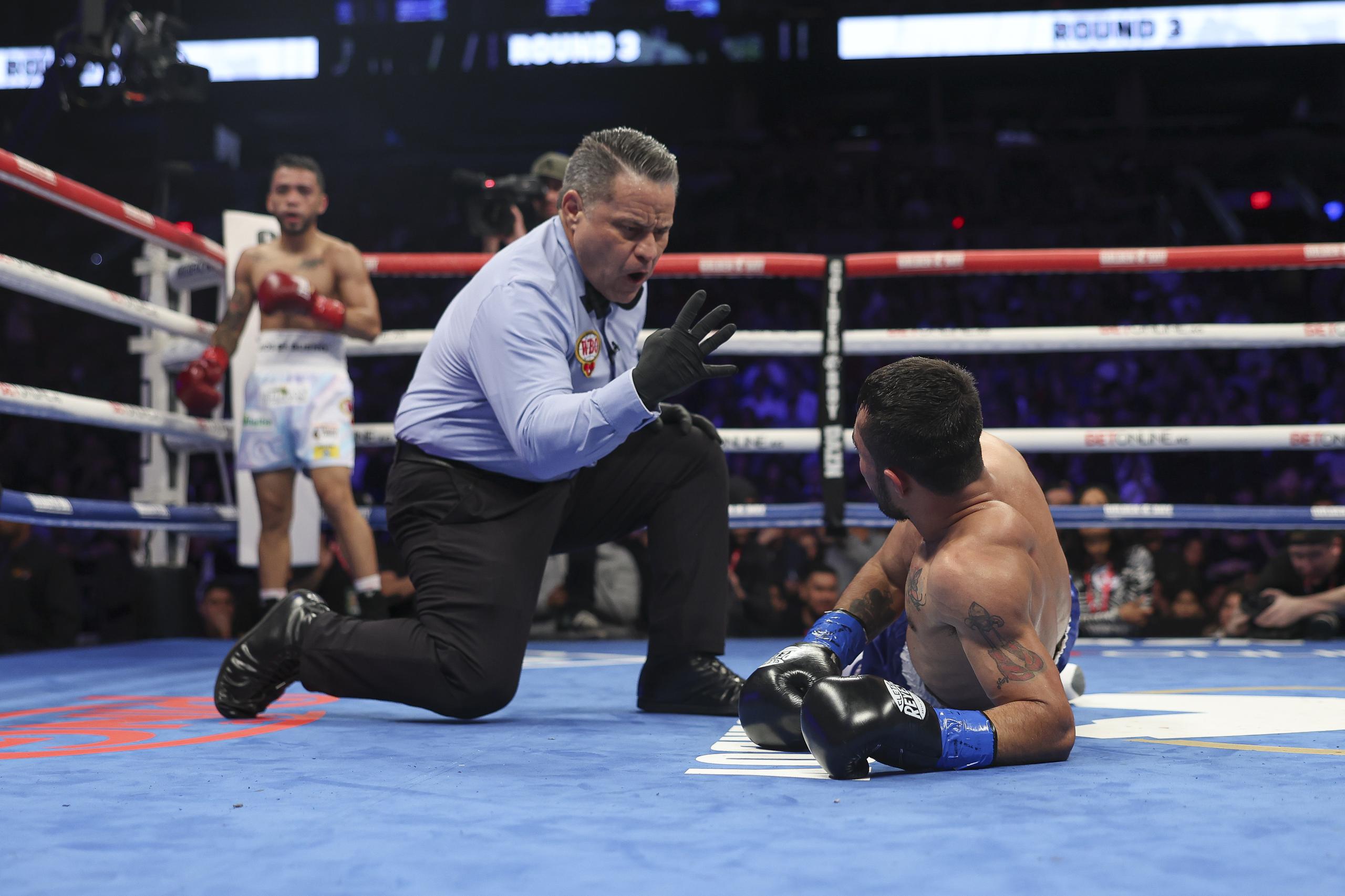 Reyneris Gutiérrez (en el suelo) recibe un conteo de protección luego de una caída en el tercer asalto de su pelea ante Oscar Collazo (de pie).