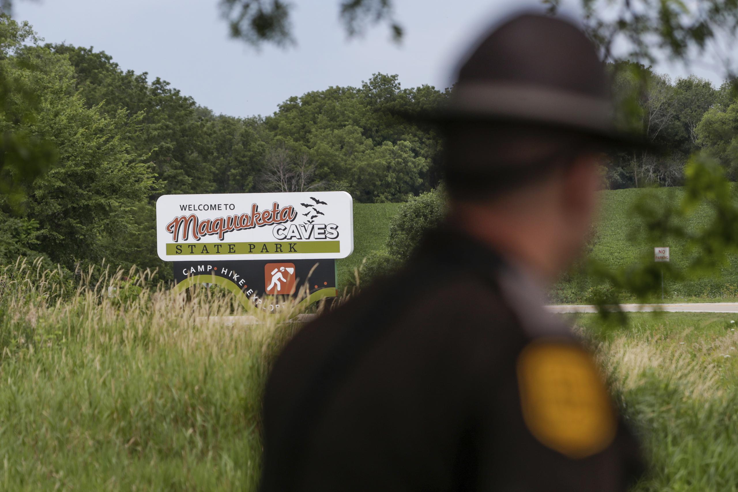 Un patrullero estatal de Iowa pasa junto a un letrero del Parque Estatal Maquoketa Caves mientras la Policía investiga un tiroteo que dejó a varias personas muertas, el viernes, 22 de julio, en Maquoketa, Iowa. El campamento fue evacuado a raíz del tiroteo. (Nikos Frazier/Quad City Times vía AP)