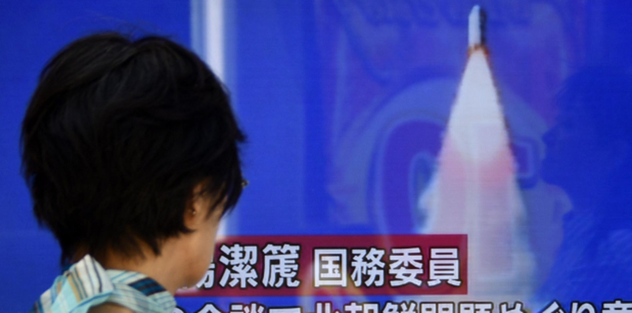 Una mujer en Tokio observa en la pantalla de un televisor en una calle noticias del lanzamiento del cohete que cayó en el Mar de Japón. (EFE)