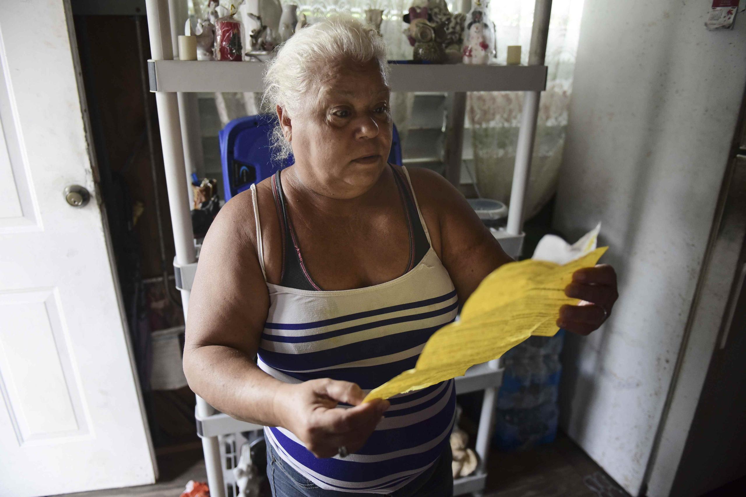 Carmen Lidia Torres Mercado revisa un documento entregado por contratistas de la FEMA tras instalar un toldo en el techo de su casa, en la barriada Figueroa en San Juan. (AP / Carlos Giusti)