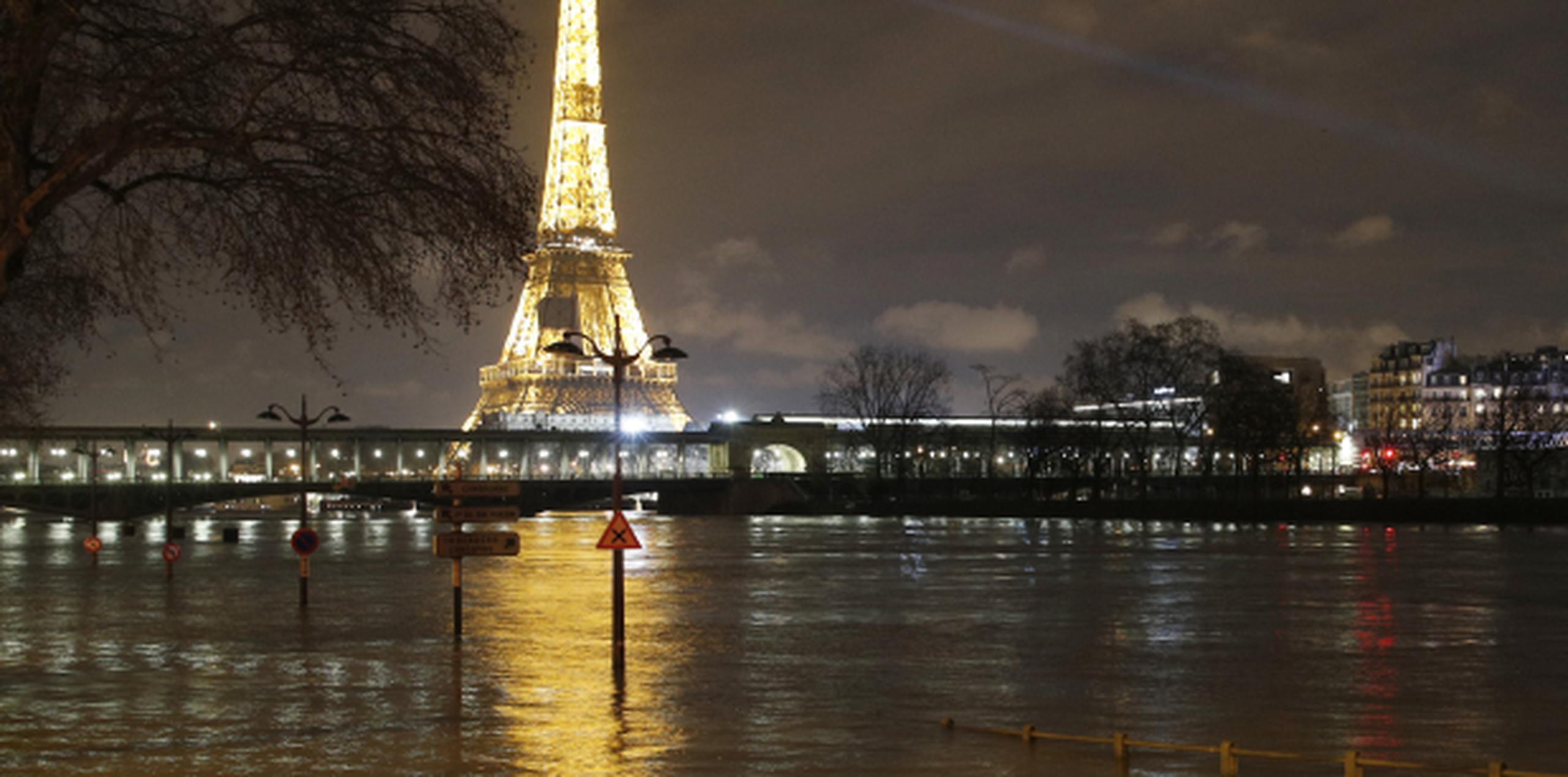La Torre Eiffel brilla como de costumbre pero su reflejo se queda esta vez en calles inundadas como esta en París, donde se puede observar los focos tapados en parte por el agua. (AP)