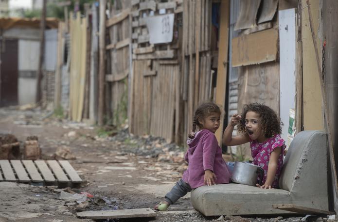 Una niña come de una cacerola en la calle en la favela Penha Brasil en Sao Paulo.