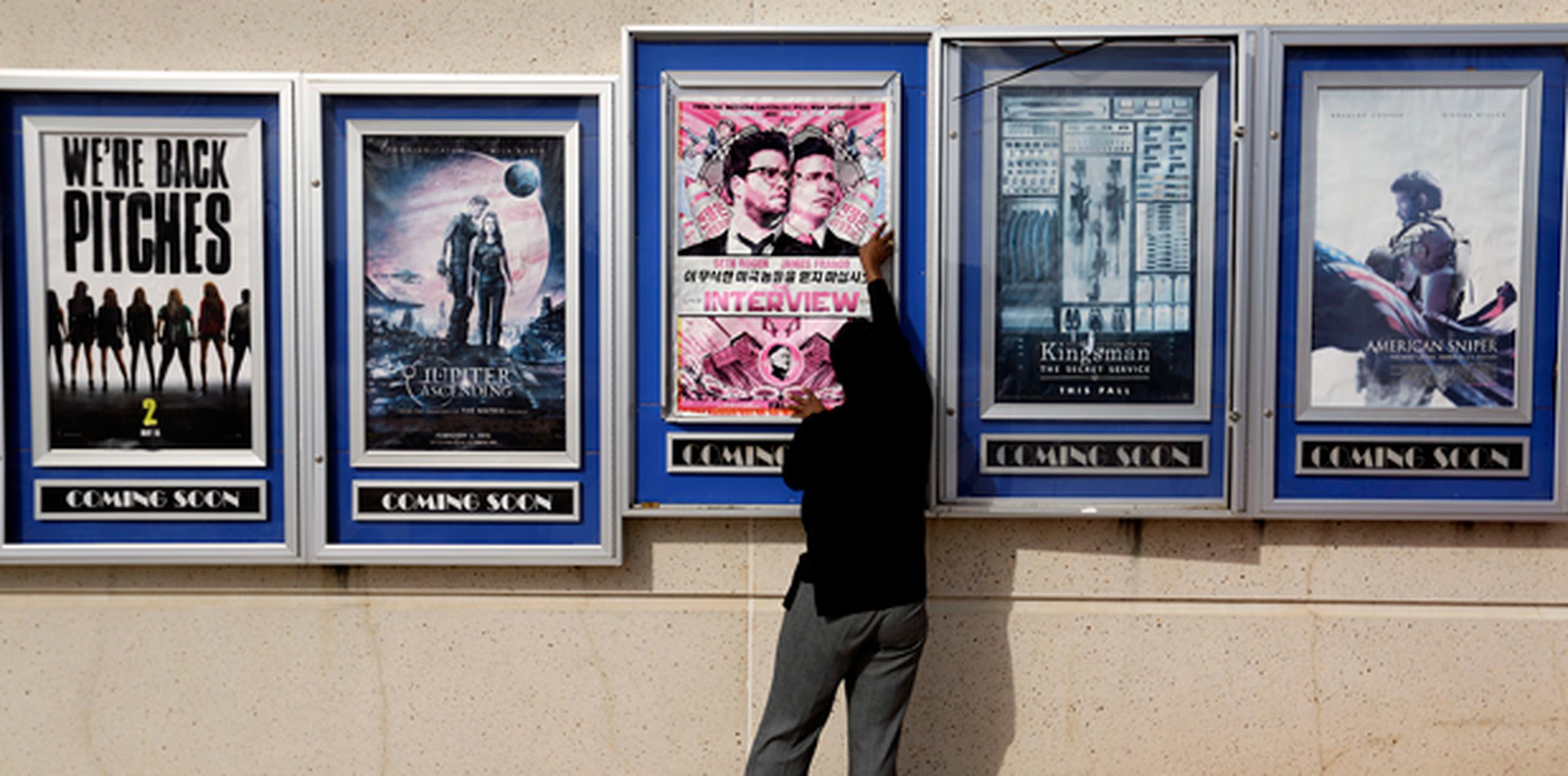Un empleado de un cine en Atlanta remueve el póster de "The Interview", película que estaba pautada para estrenar el 25 de diciembre. (AP)