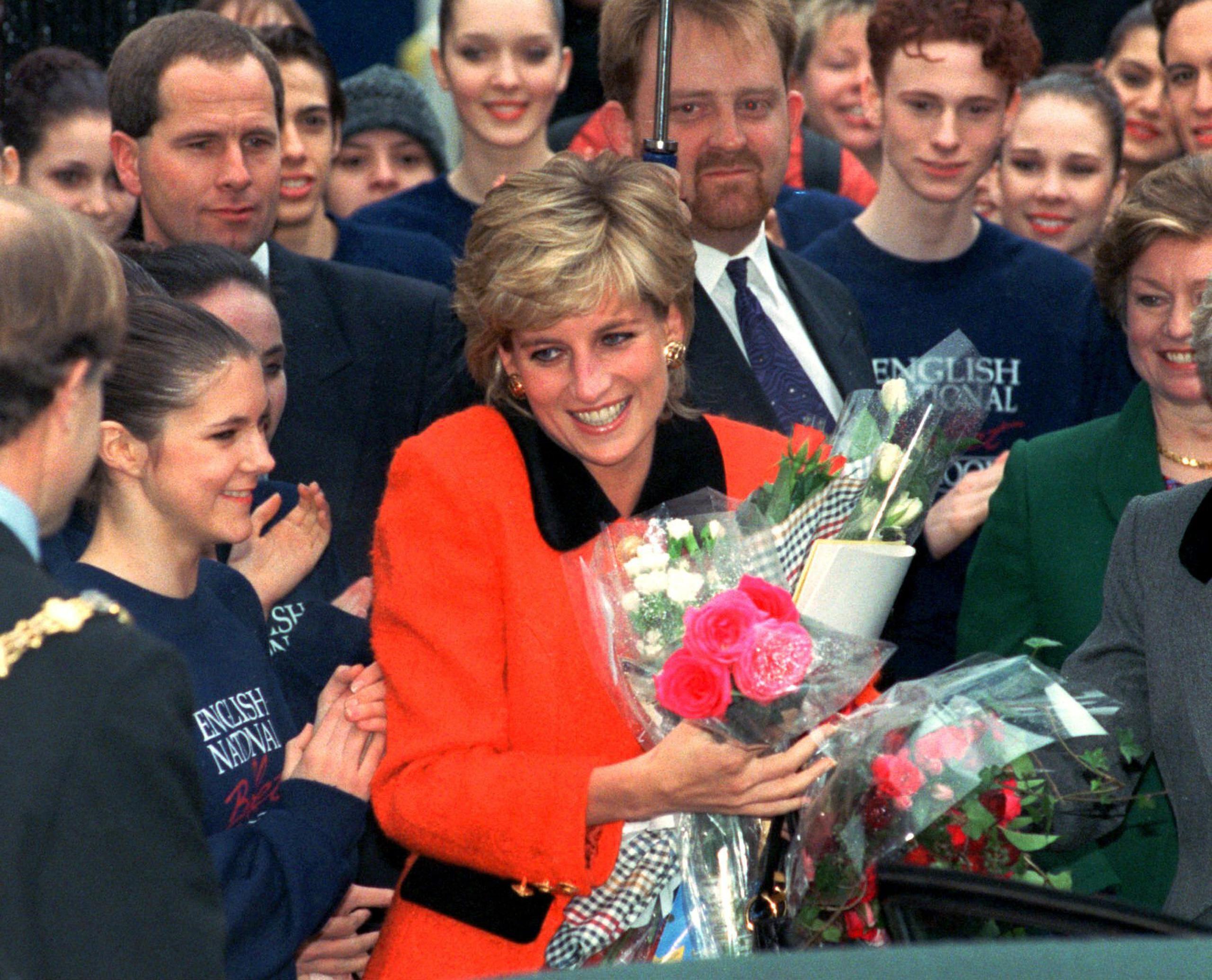 En esta fotografía del 6 de diciembre de 1995 Diana, la princesa de Gales, sonríe tras recibir un ramo de flores de admiradores al salir de la ceremonia inaugural de la escuela del Ballet Nacional de Inglaterra.