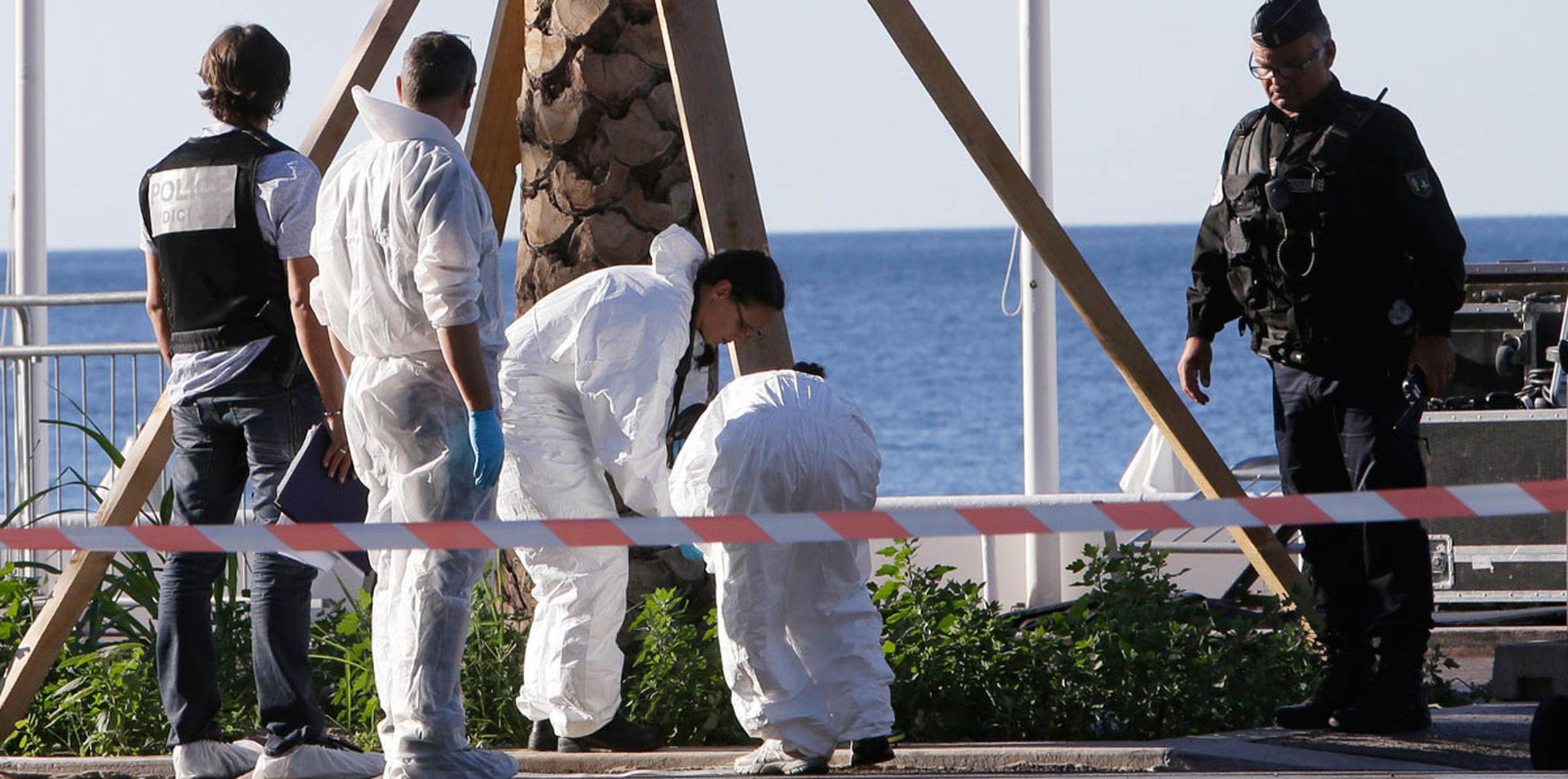 Investigadores inspeccionan la escena donde ayer el conductor de un camión atropelló intencionalmente a decenas de personas en la costa de Niza. (AP)