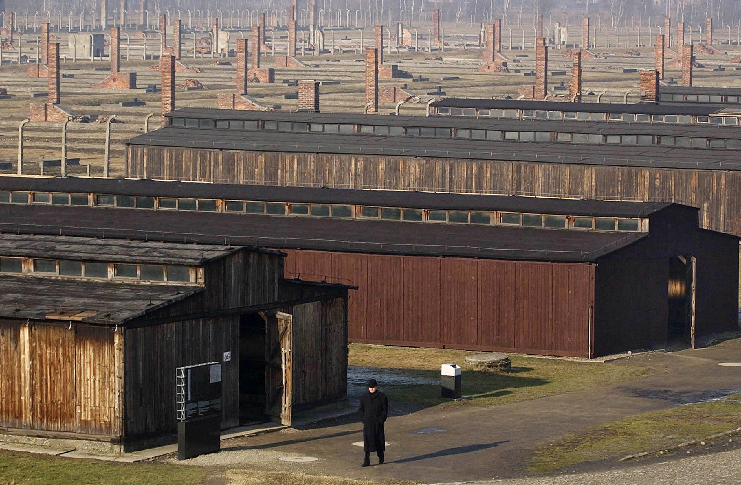 Fotografía de archivo del 17 de enero de 2005 de un visitante caminando junto a los barracones de madera del antiguo campo de exterminio nazi de Auschwitz-Birkenau en Oswiecim, Polonia. (AP Foto/Czarek Sokolowski, Archivo)