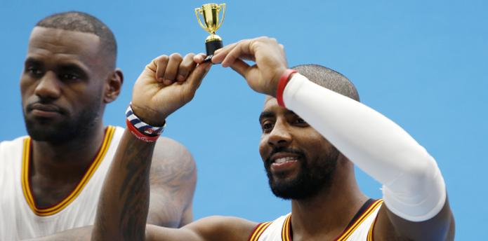 El armador estelar Kyre Irving eleva un diminuto trofeo durante la sesión de fotos de los Cavaliers. (Prensa Asociada)