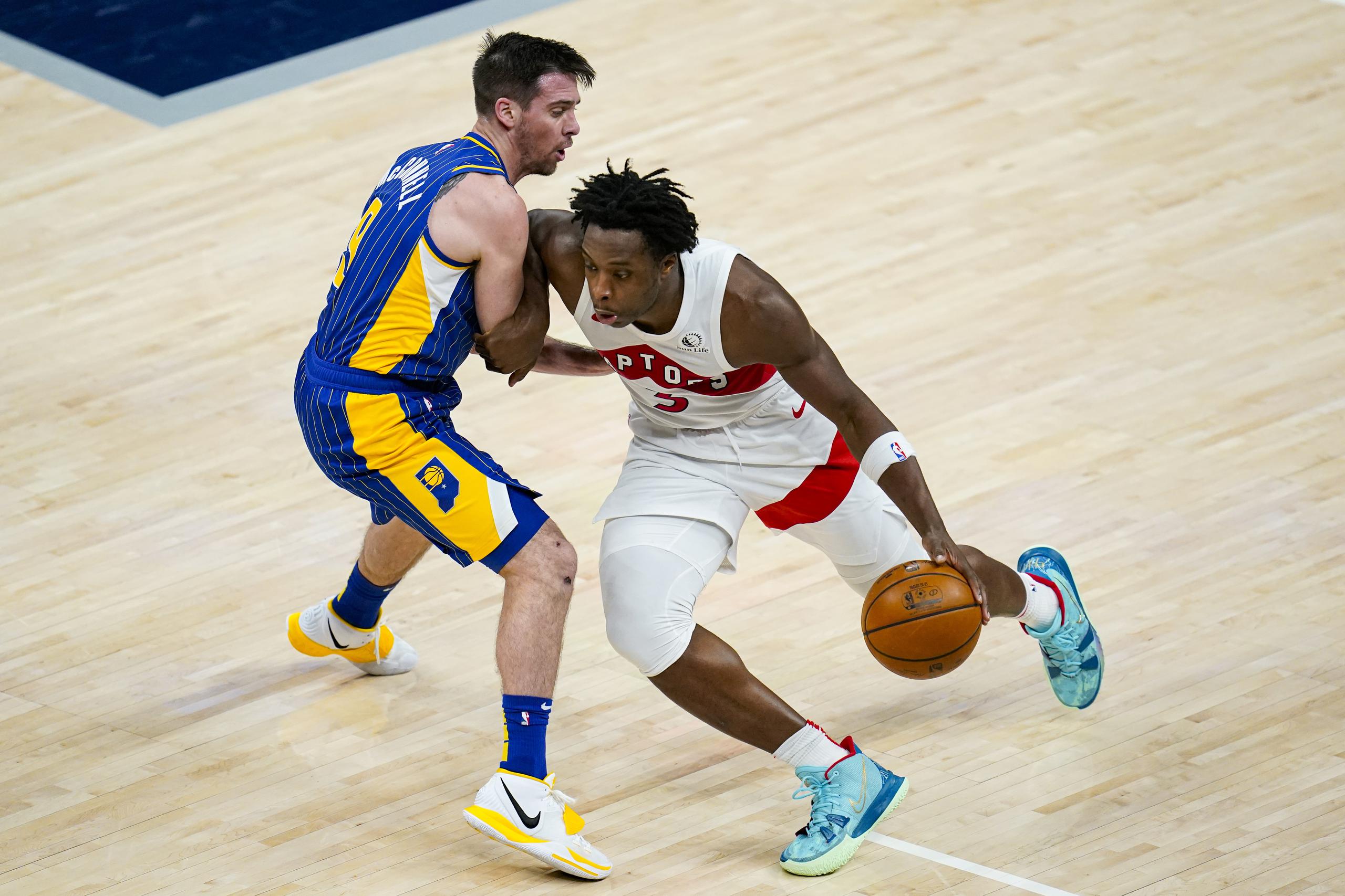 El alero de los Raptors de Toronto OG Anunoby avanza con el balón hacia la canasta mientras lo defiende el base de los Pacers de Indiana T.J. McConnell.