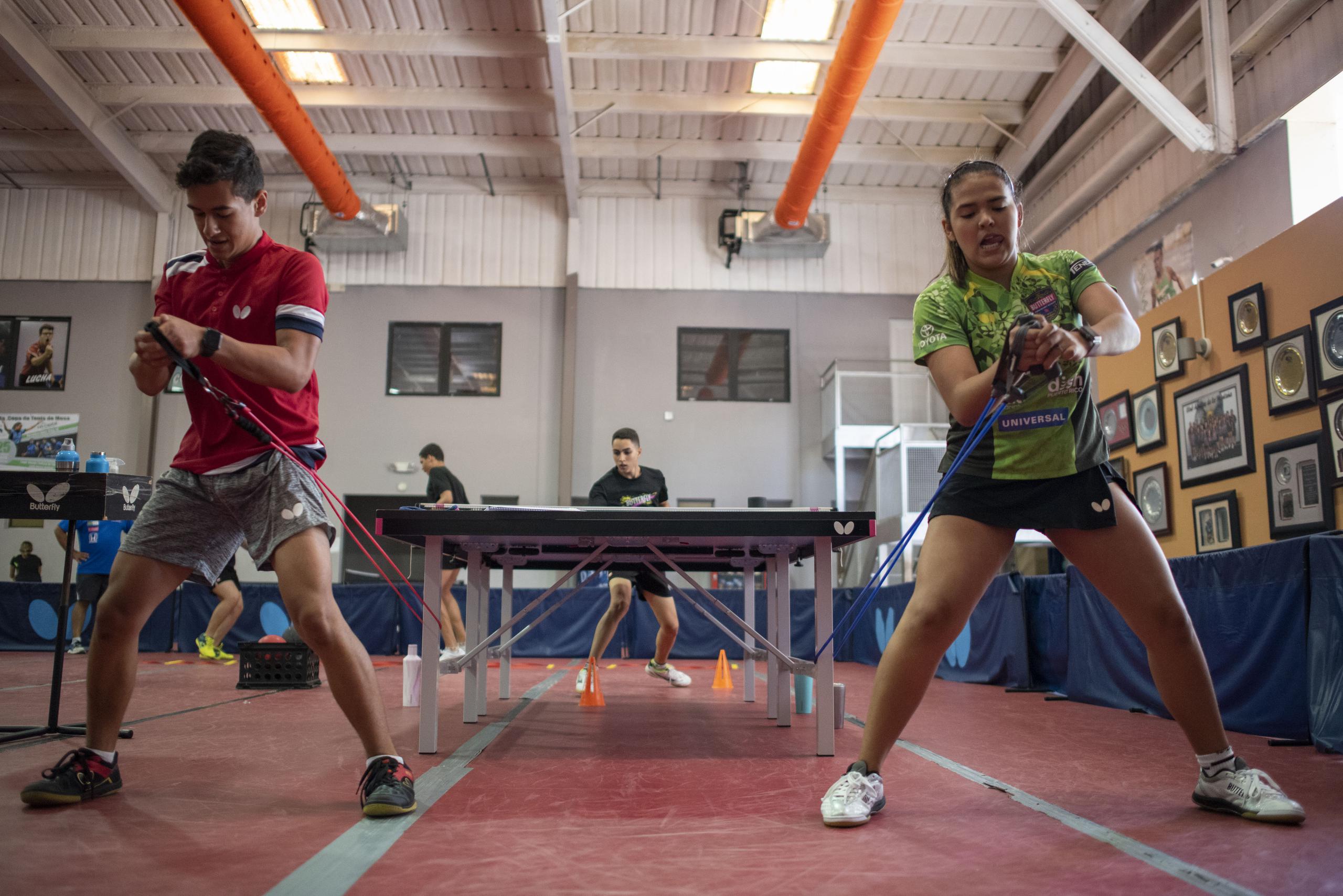Adriana Díaz y otro joven hacen una rutina física en preparación para ir a la mesa a jugar.