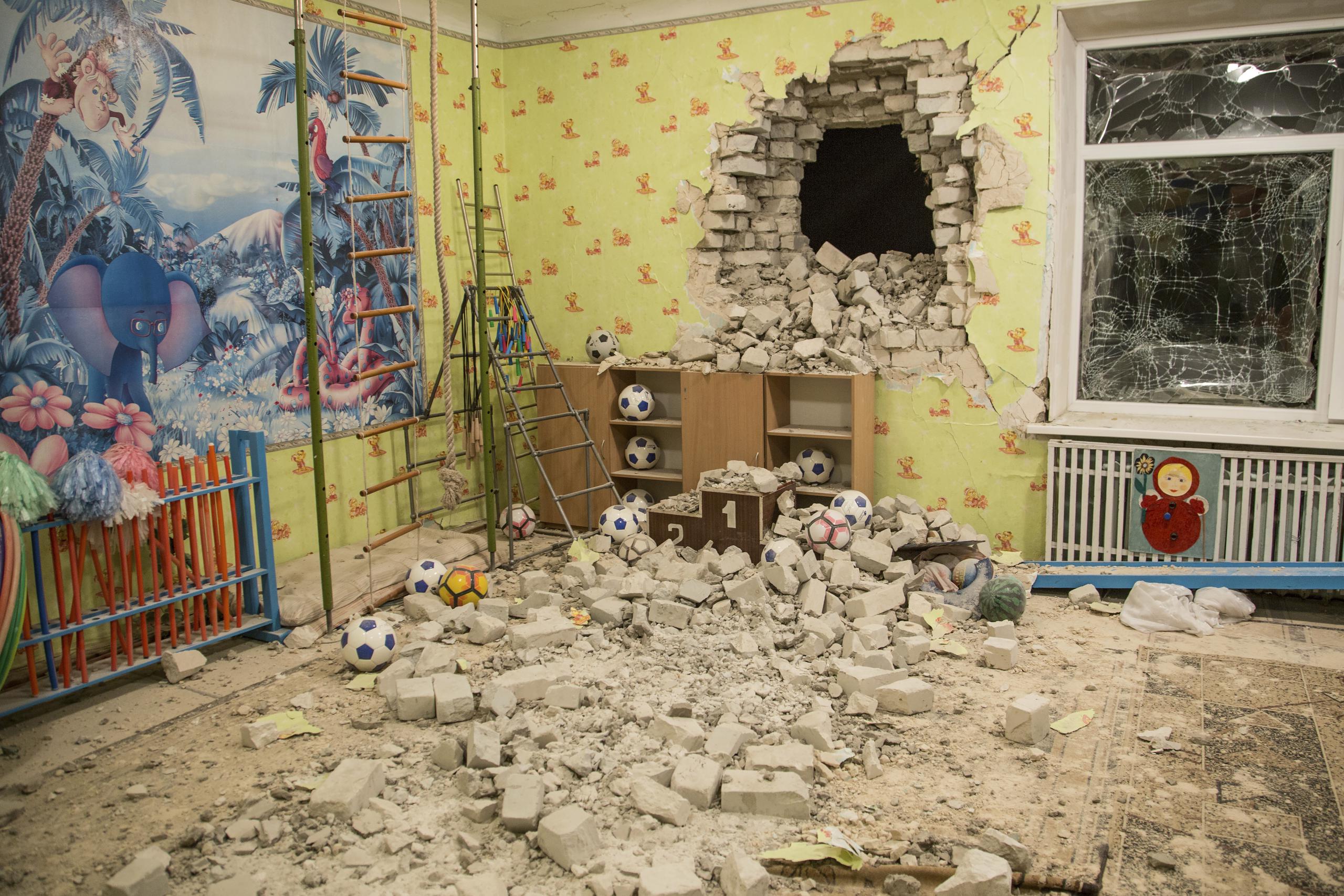 Ladrillos y escombros mezclados con juguetes bajo una pared dañada tras el ataque a un jardín de infantes en el asentamiento de Stanytsia Luhanska.