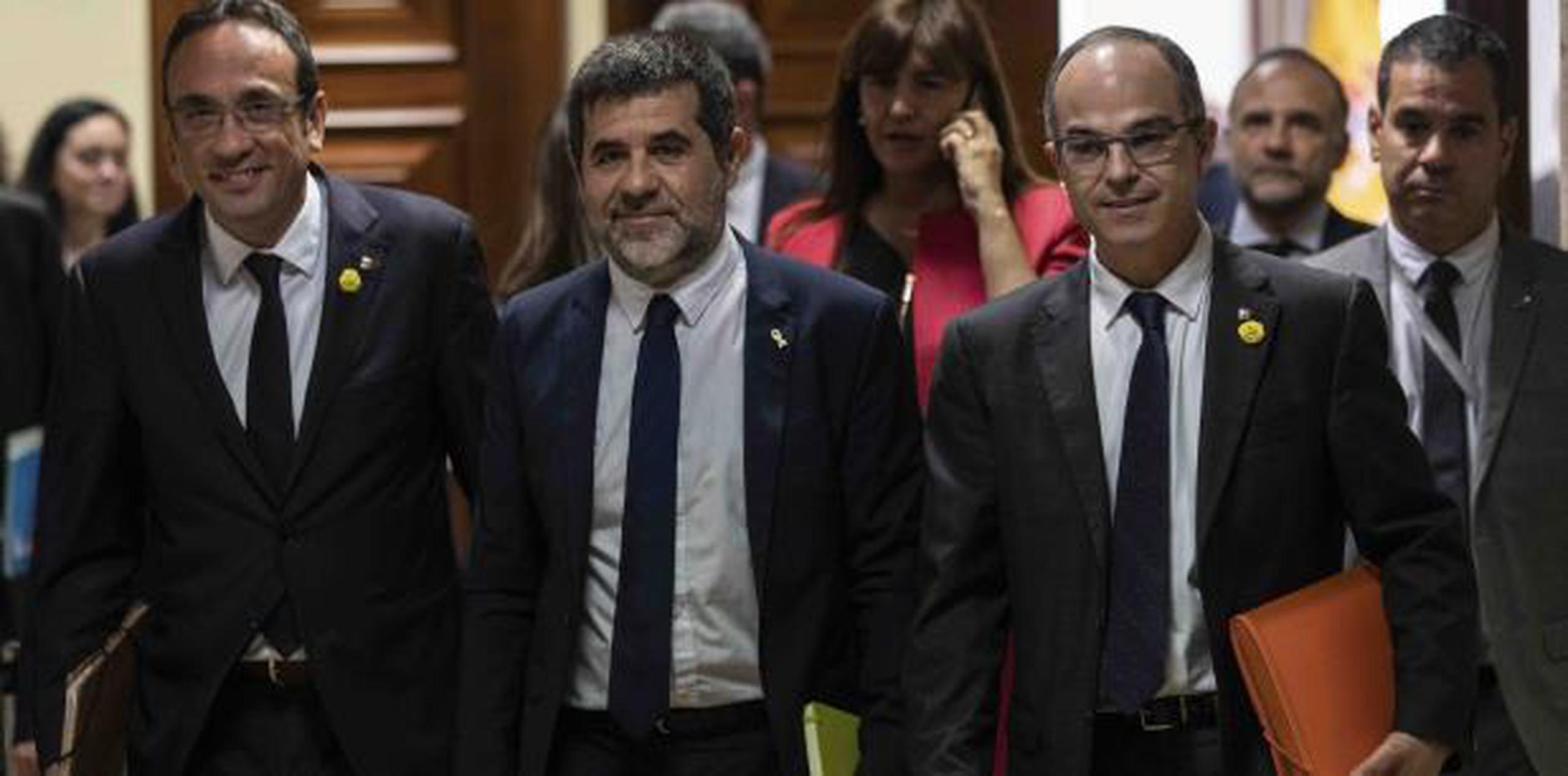 Desde la izquierda Josep Rull, Jordi Sánchez y Jordi Turull sonríen en su visita al parlamento para recoger sus credenciales como integrantes del cuerpo legislativo. (AP)