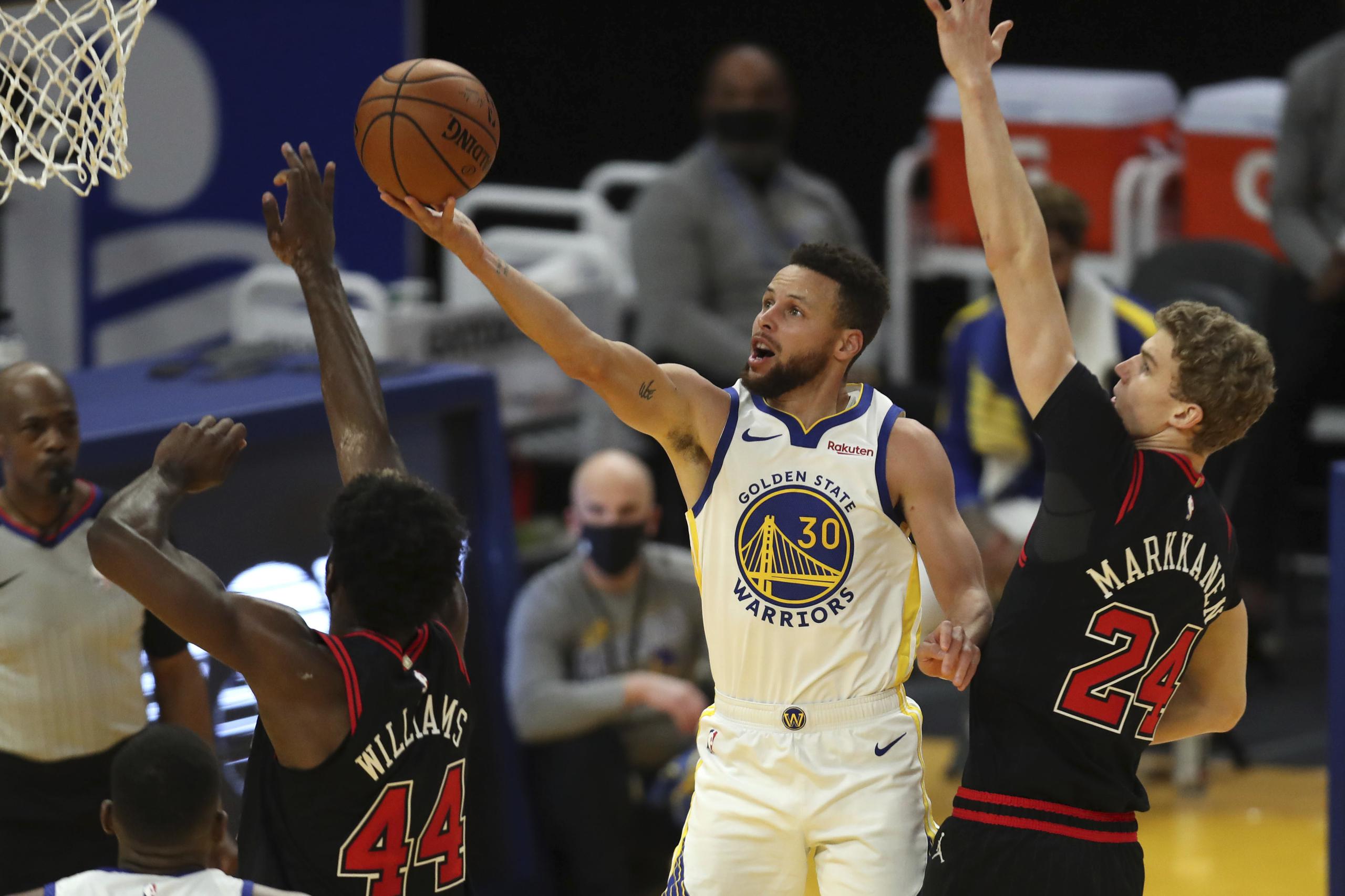 El base de los Warriors de Golden State, Steph Curry, dispara entre la defensiva del alero Lauri Markkanen y el alero Patrick Williams, de los Bulls de Chicago.