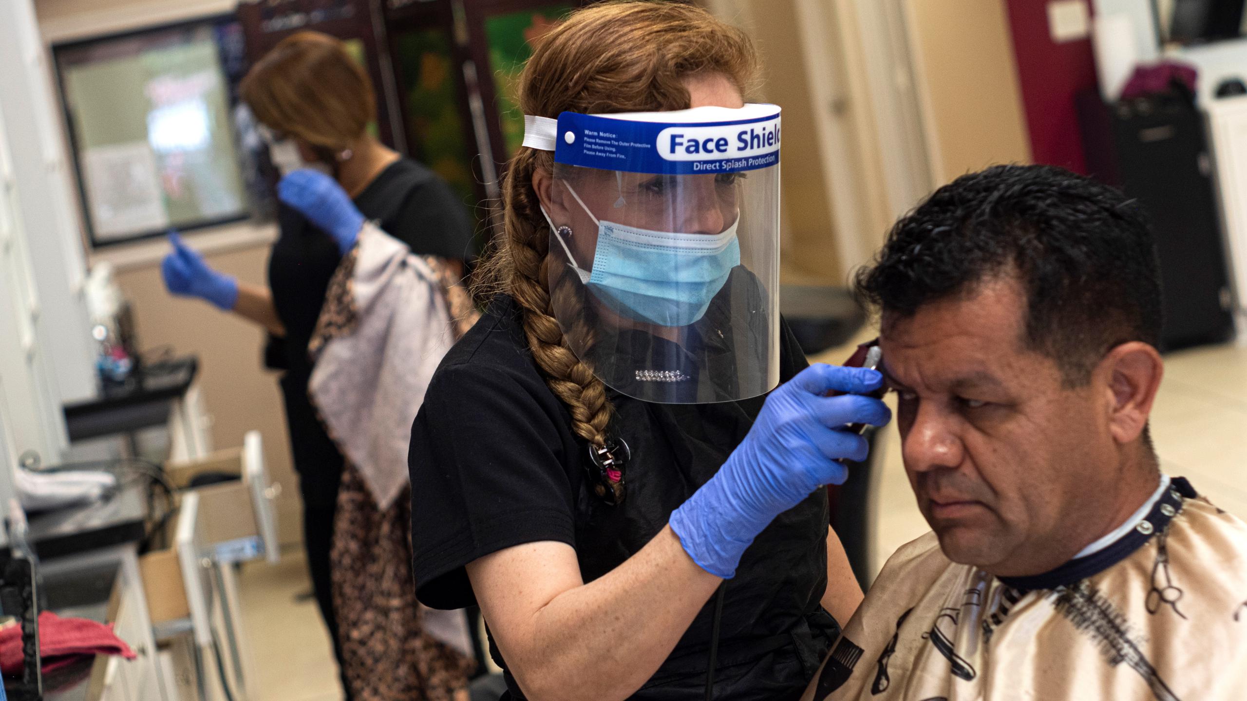 María Ochoa realiza un corte de cabello a un cliente en su local ubicado en el noreste de Houston, Texas
