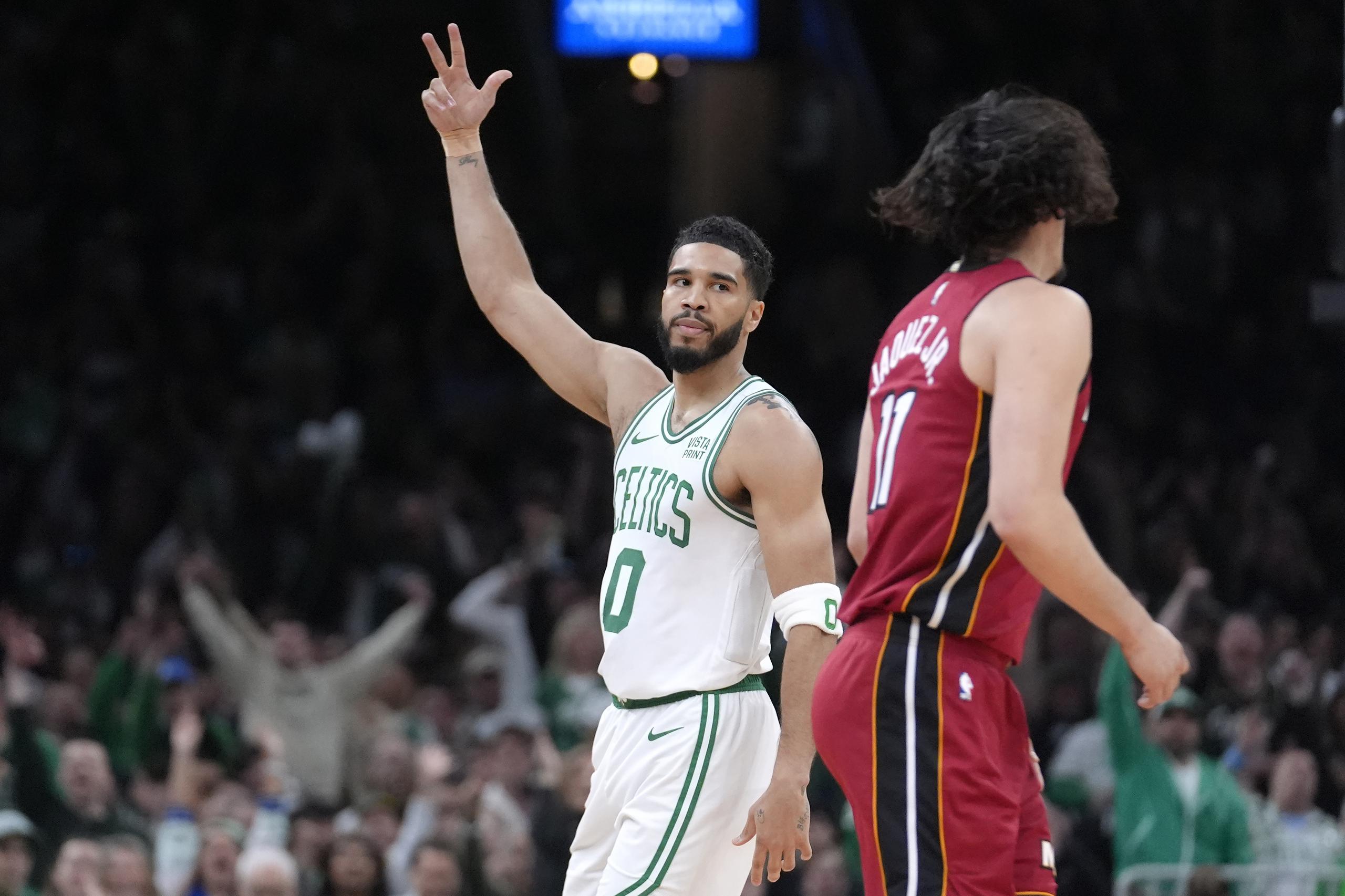 El alero de los Celtics de Boston Jayson Tatum (0) celebra frente al armador mexicano del Heat de Miami Jaime Jaquez Jr. (11), durante la primera mitad del Juego 1 de la serie de primera ronda de postemporada de la NBA, el domingo 21 de abril de 2024, en Boston.