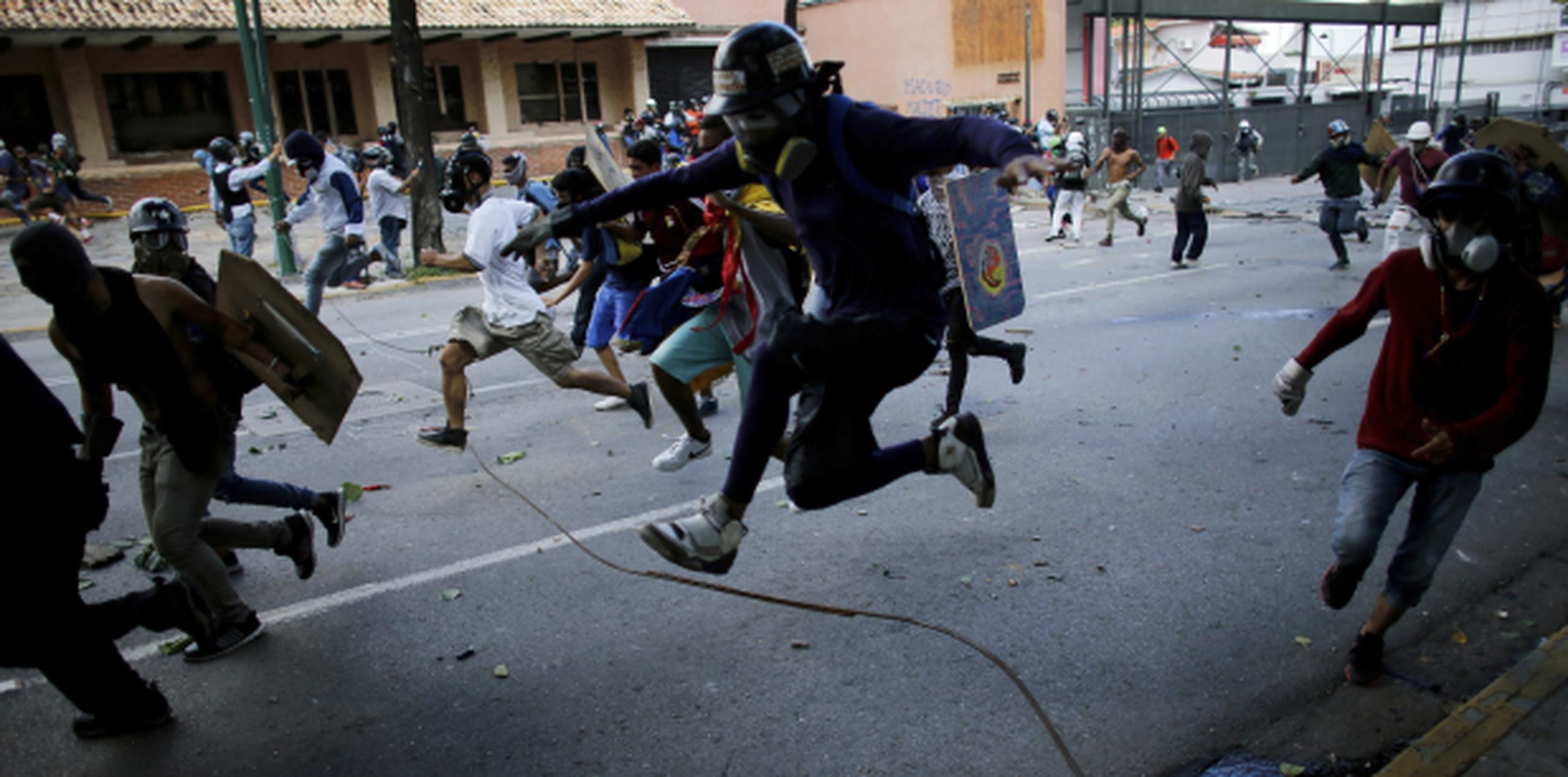 Manifestantes corren por calles de Caracas en medio de enfrentamientos con miembros de la Guardia Nacional Bolivariana. (AP /Ariana Cubillos)
