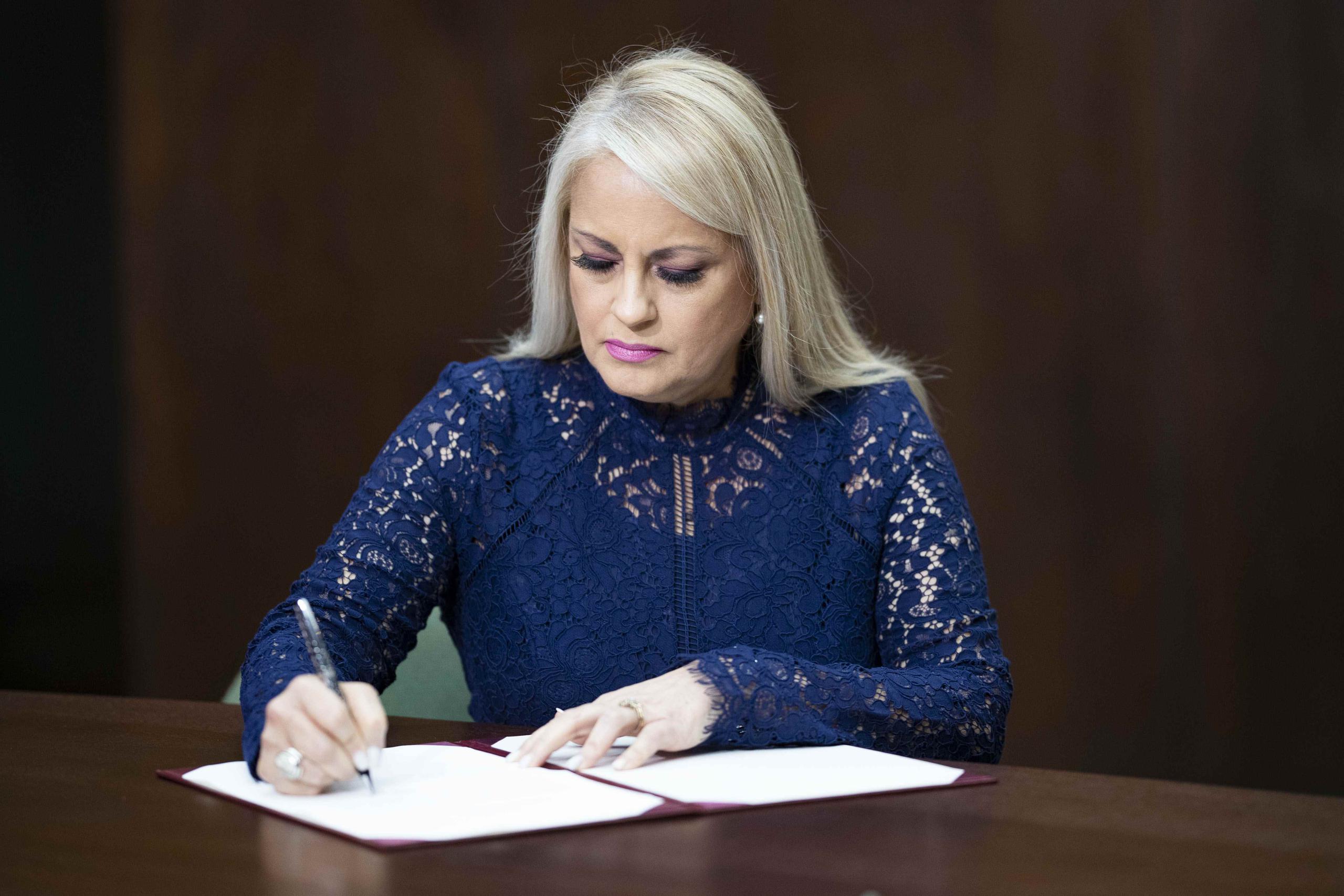La nueva gobernadora Wanda Vázquez firma el documento oficializando su juramentación.
