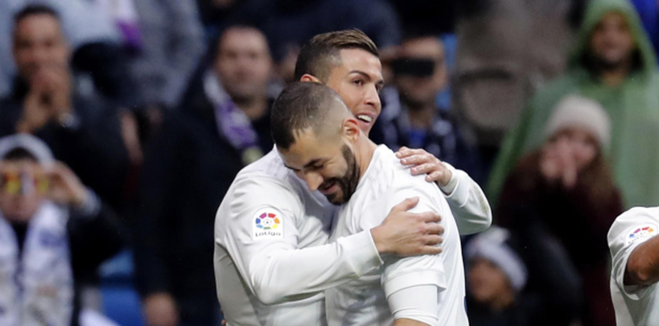 El delantero portugués del Real Madrid, Cristiano Ronaldo (izquierda) celebra con su compañero, el francés Karim Benzema, el gol marcado ante el Sporting, el segundo del equipo, durante el partido de la decimotercera jornada de Liga que disputan en el estadio Santiago Bernabéu de Madrid, el pasado 26 de noviembre. (EFE / Juan Carlos Hidalgo)