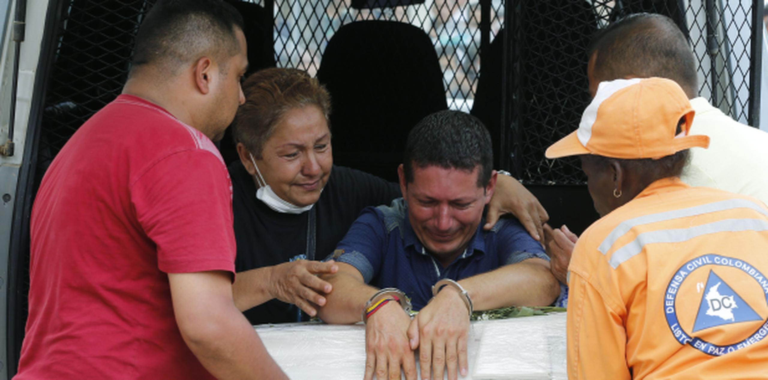 El preso Ricardo Alegría (centro) llora sobre el féretro con los restos mortales de su hija, en Mocoa, Colombia. (AP / Fernando Vergara)