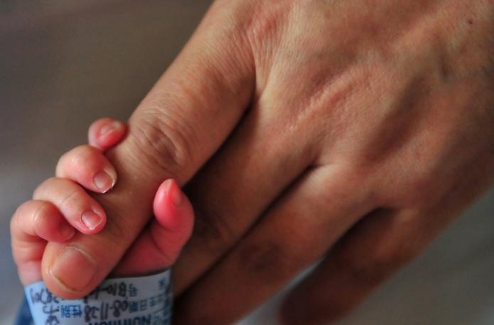 A newborn baby holds onto his mother's finger at a hospital in Beijing on December 1, 2008. The Chinese government has insisted extensive measures have been taken to ensure melamine is no longer in China's dairy supply after admitting that a total of 294,000 children had fallen ill from consuming dairy products tainted with the industrial chemical, normally used to make plastics, after it emerged in September that melamine had been routinely mixed into Chinese milk and dairy products to give  the impression of having a higher protein content. The scandal quickly became a global problem, with Chinese dairy products around the world recalled or banned after they were found to be tainted with the industrial chemical. AFP PHOTO/Frederic J. BROWN