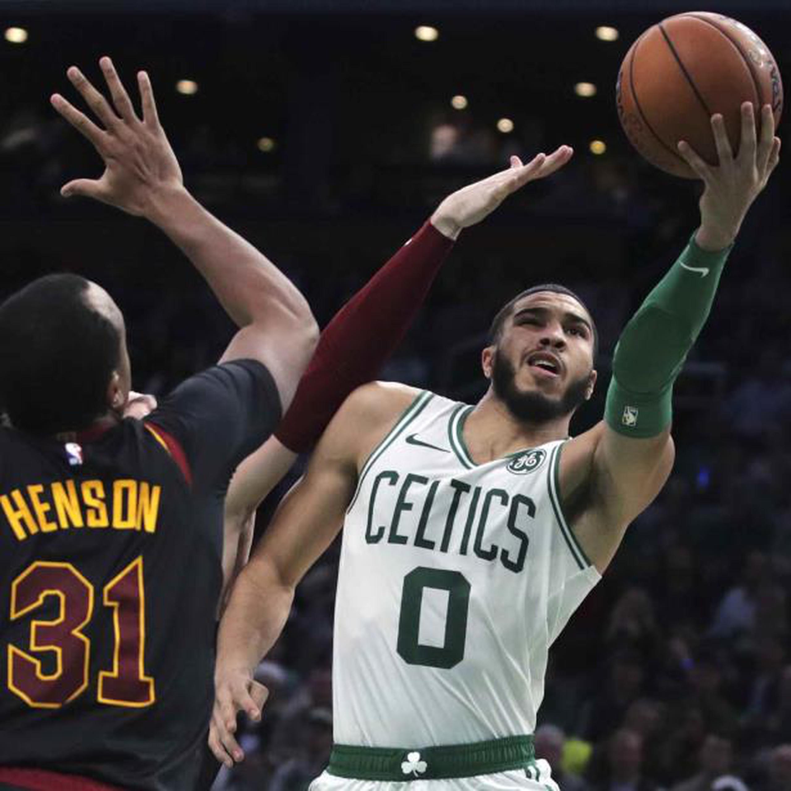 Jayson Tatum, de los Celtics de Boston, logra evadir a dos defensores de los Cavaliers de Cleveland de camino al canasto durante el desafío de anoche en Boston. (AP / Charles Krupa)
