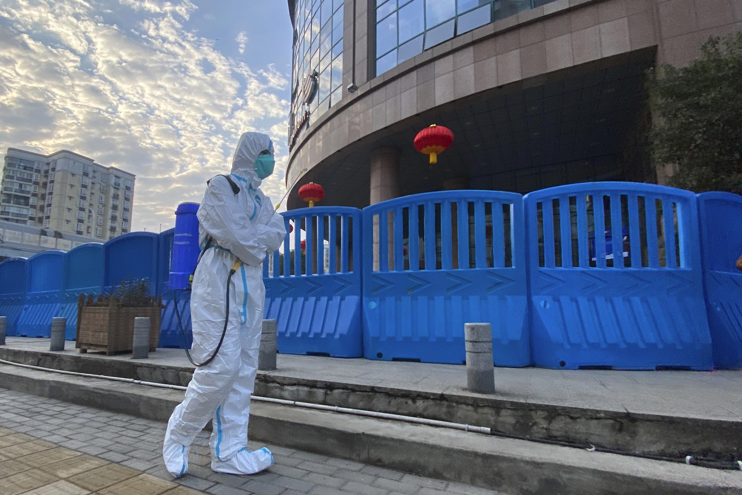 Un trabajador con equipo de protección camina afuera del Hospital Central de Wuhan, en China, donde el médico Li Wenliang hizo sonar las armas en los primeros días de la pandemia de coronavirus.