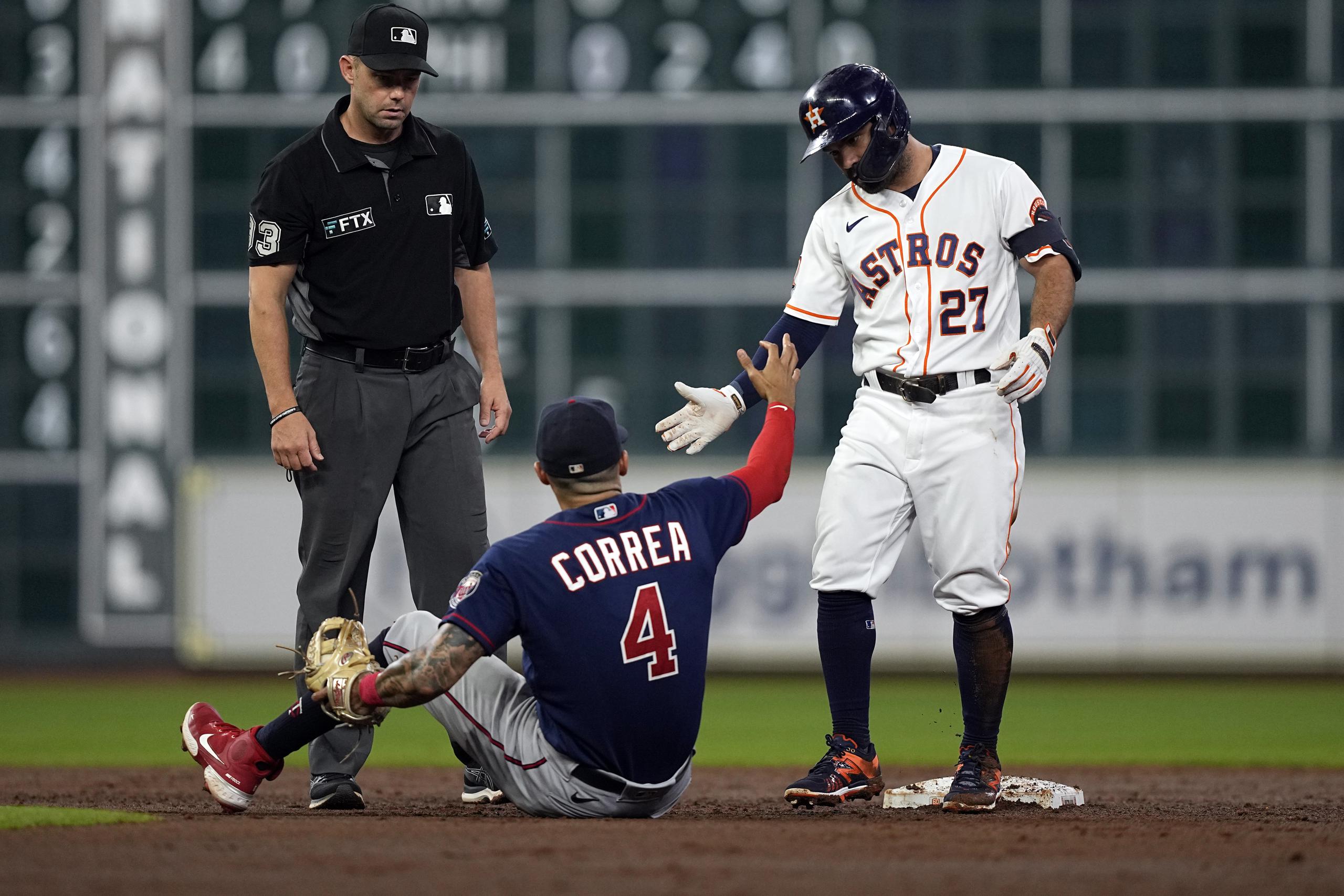 José Altuve (27), de los Astros de Houston, ayuda a levantarse a Carlos Correa, de los Twins de Minnesota, luego de que Correa lo pusiera fuera en segunda base.
