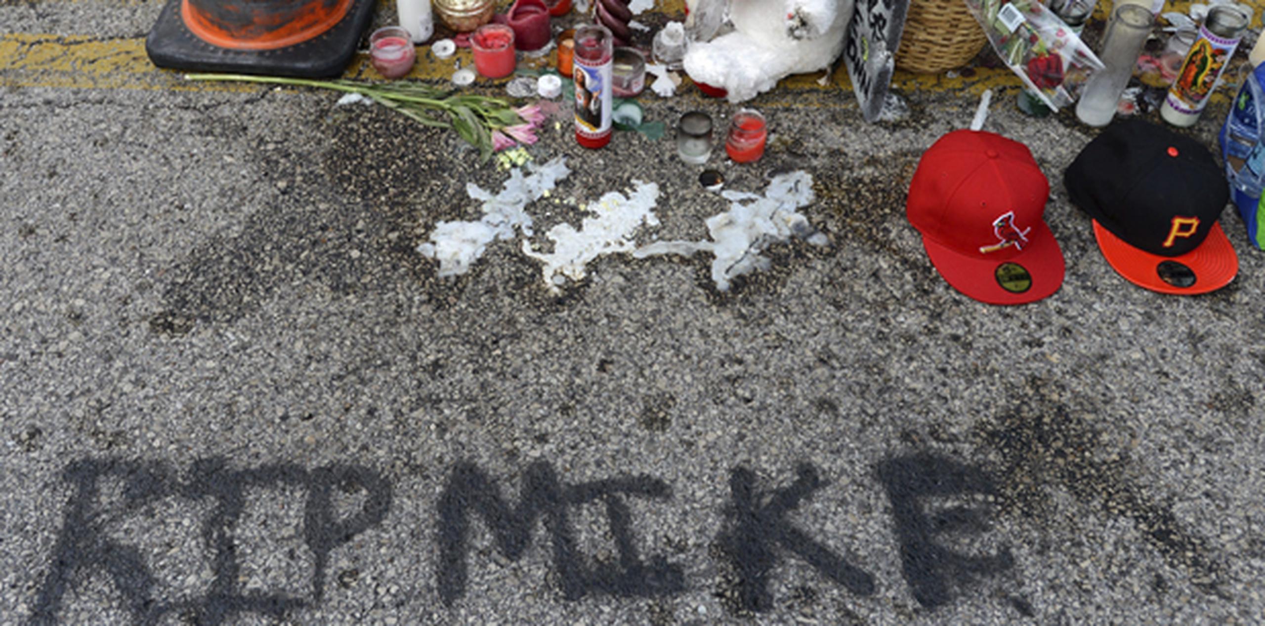 Flores, velas y peluches marcan el lugar donde falleció el joven Michael Brown en Ferguson, Misuri.  (EFE)