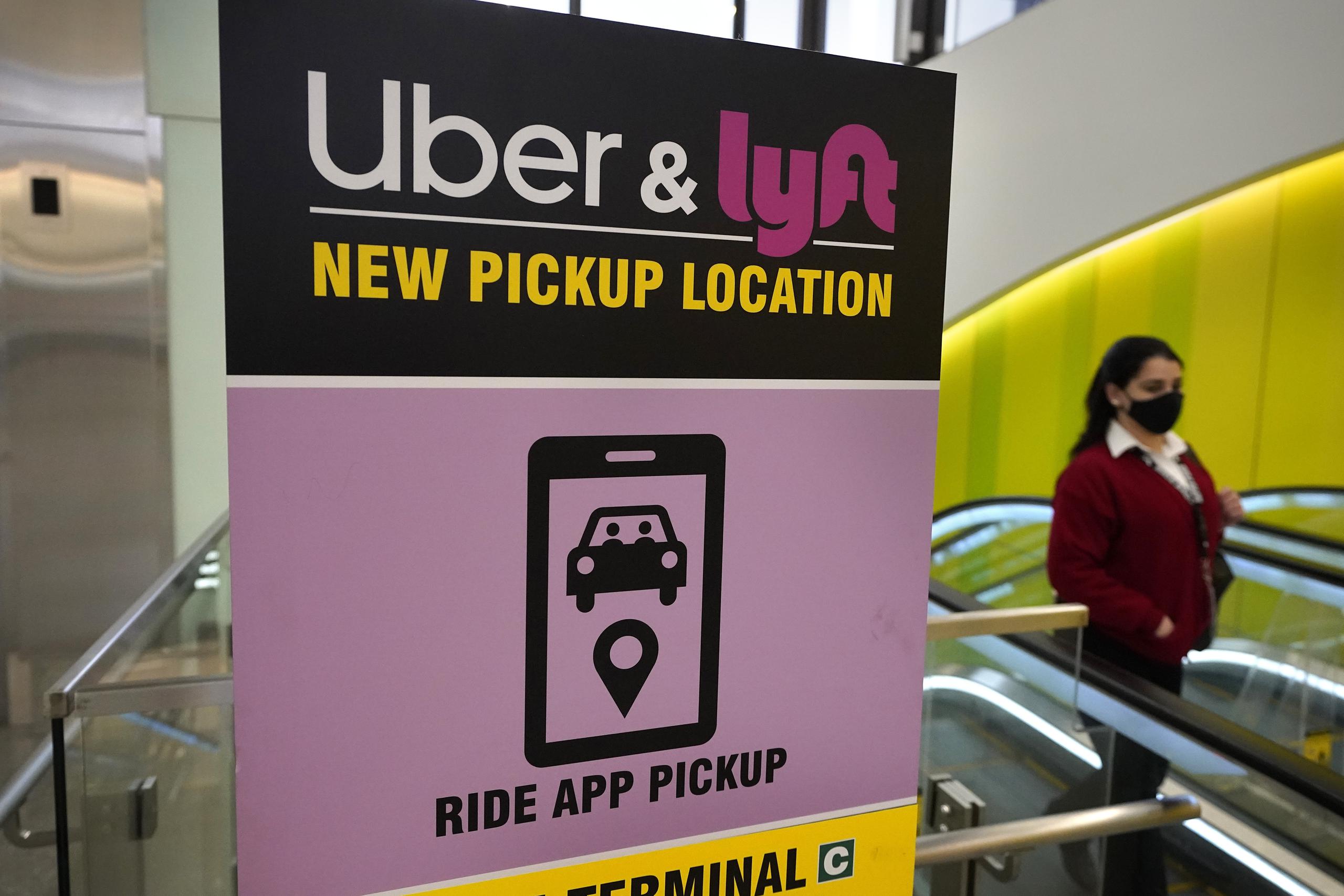 Una persona pasa por un letrero que ofrece a las personas dónde ser recogidas por un vehículo de Uber o Lyft en el Aeropuerto Internacional Logan en Boston.
