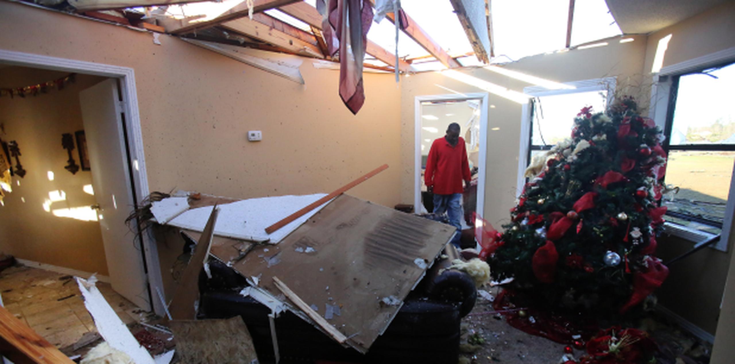 Un hombre camina junto a un árbol de Navidad en medio del destrozo provocado por un tornado en su casa en Holly Springs, Mississippi. (Stan Carroll/The Commercial Appeal via AP)
