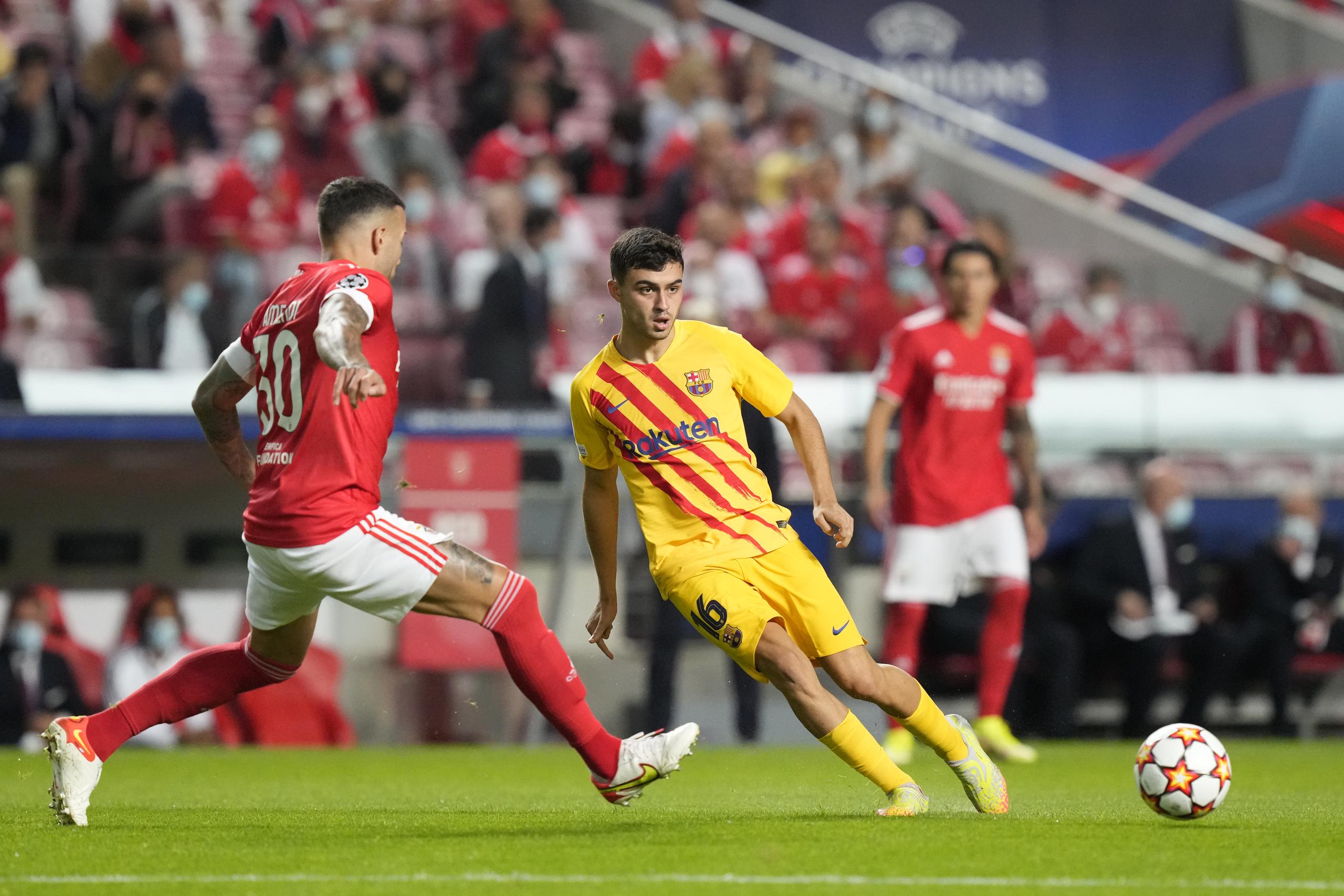 El volante Pedri (centro) del Barcelona pasa el balón ante la marca del zaguero Nicolás Otamendi del Benfica durante el partido de la Liga de Campeones, el miércoles 29 de septiembre de 2021, en Lisboa.