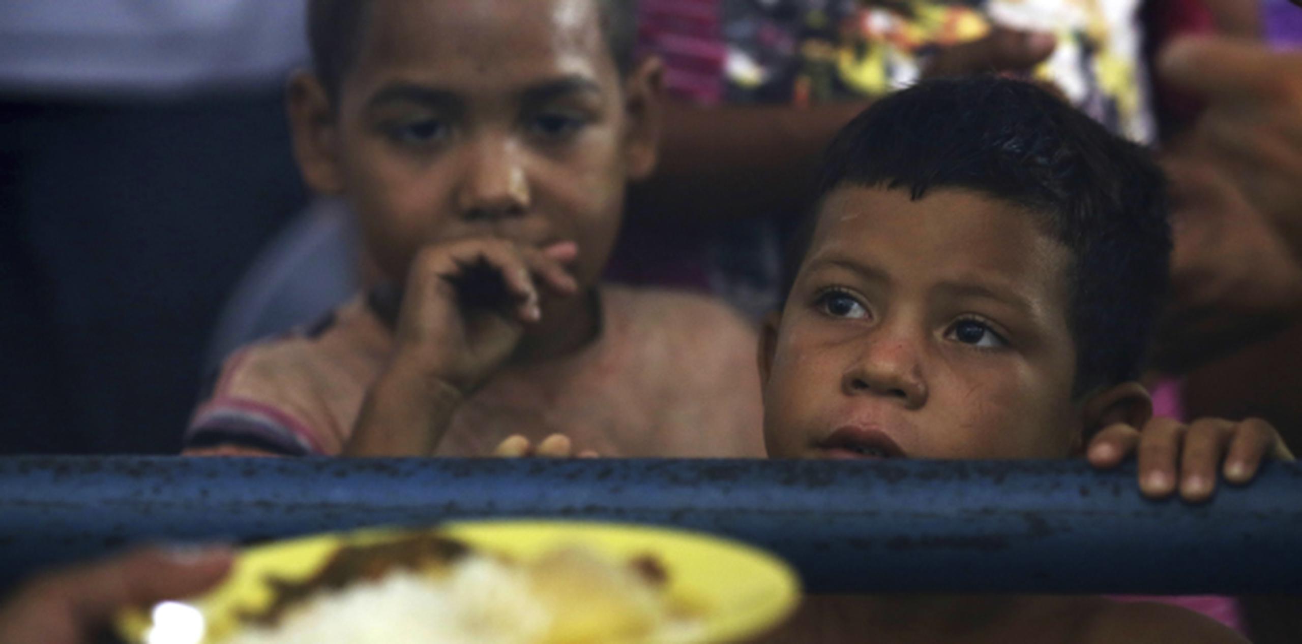 Niños venezolanos esperan para recibir una ración de comida en un centro para migrantes habilitado en el Gimnasio Tancredo Neves, en Boa Vista, en el estado de Roraima, Brasil. (AP /Eraldo Peres)