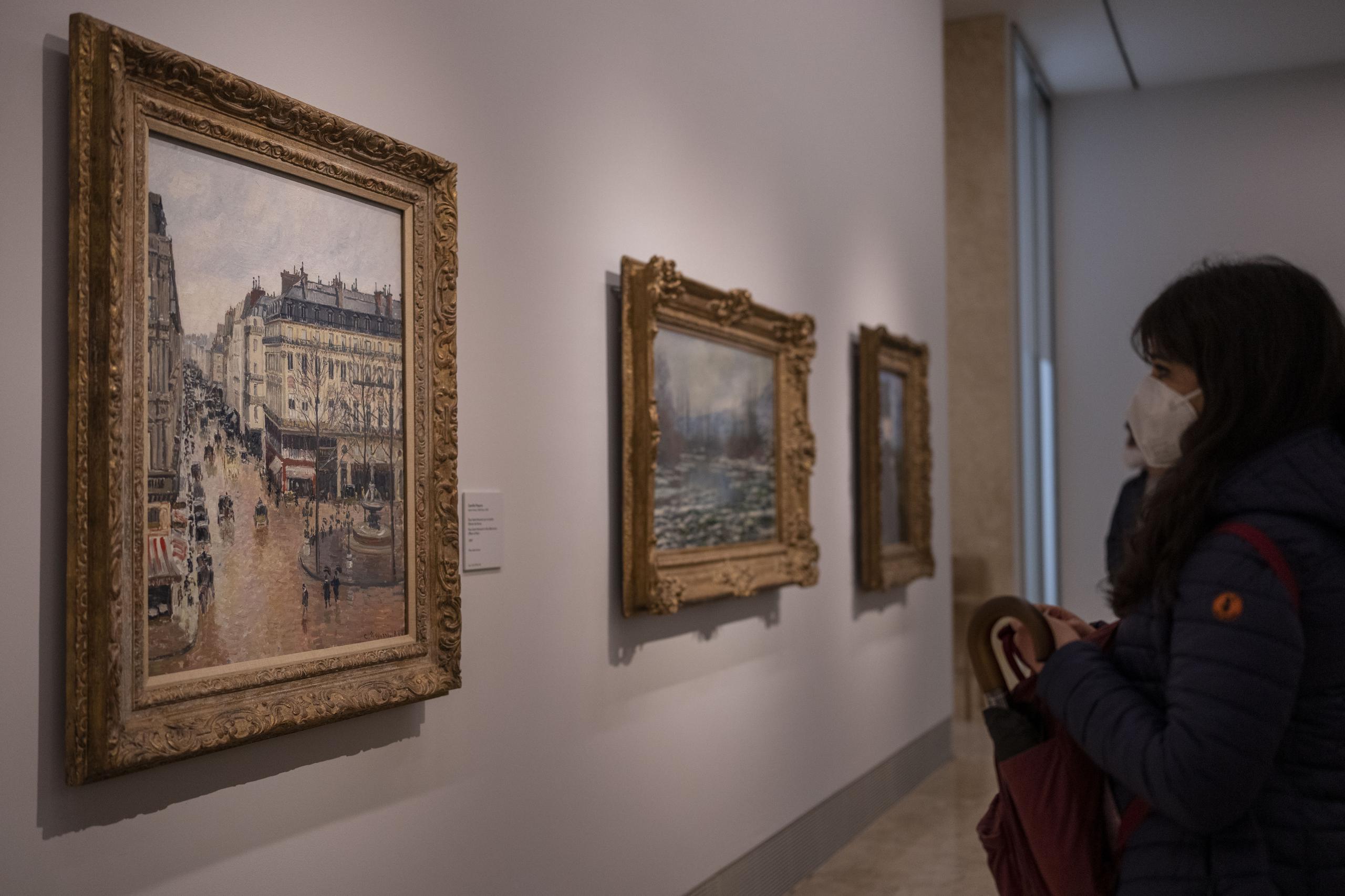 Una mujer mira la pintura impresionista "Rue St.-Honore, Apres-Midi, Effet de Pluie" (“Calle Saint-Honoré por la tarde, efecto de lluvia”) de Camille Pissarro de 1897 en el Museo Thyssen-Bornemisza en Madrid, España, el 22 de abril de 2022. (Foto AP/Manu Fernandez)