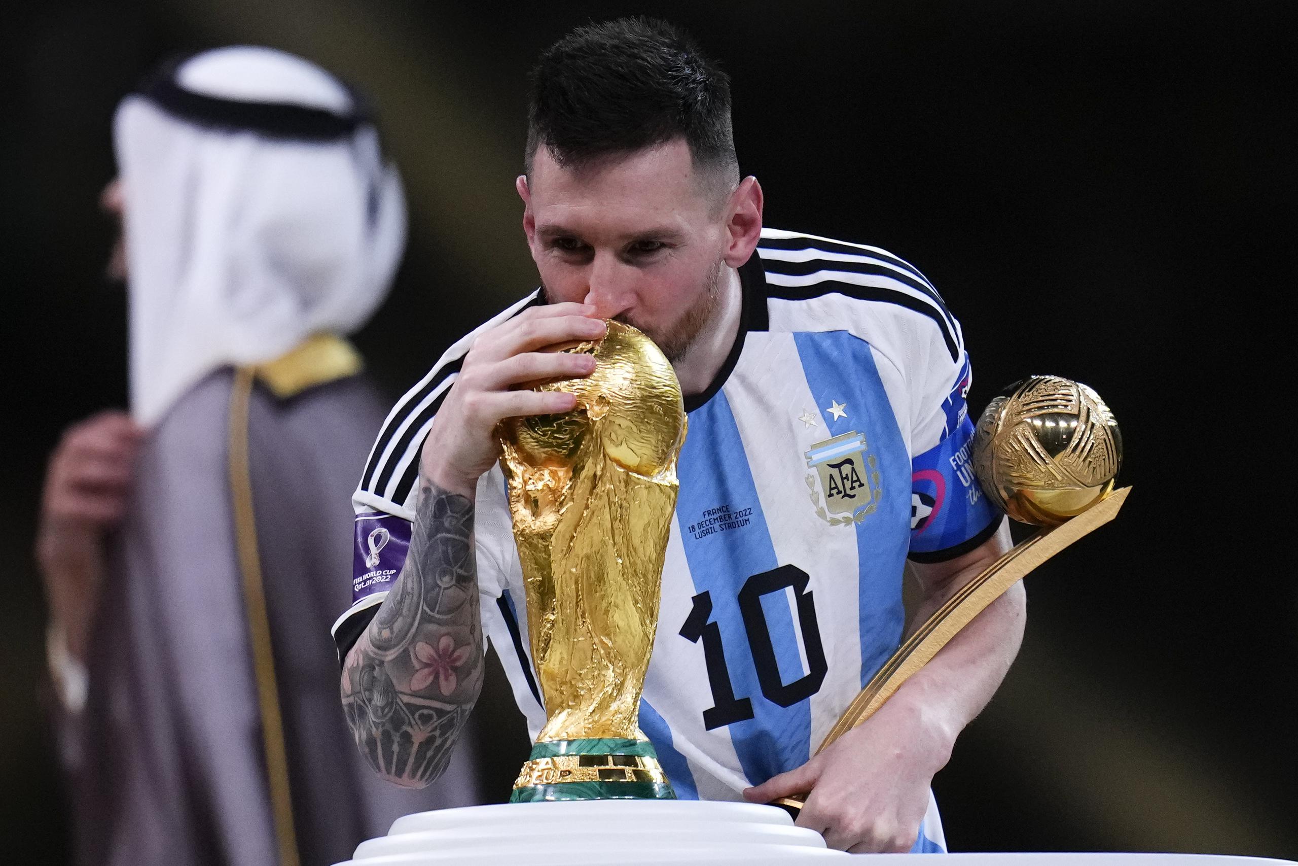 Lionel Messi besa el trofeo de la Copa del Mundo mientras sostiene el premio al mejor jugador del torneo tras la victorias 4-2 ante Francia por penales en la final.