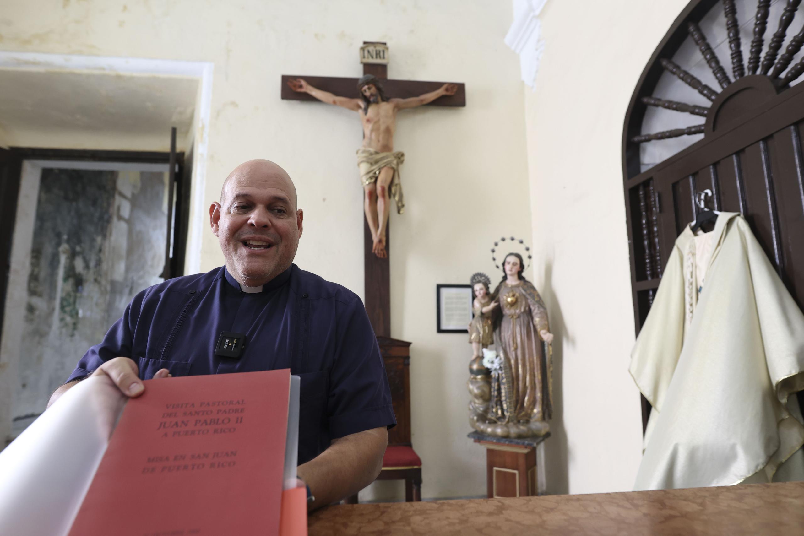 Sauniel Rondón Silva, diácono de la Catedral del Viejo San Juan, muestra el libro de oraciones que utilizó el papa durante la misa. Colgado a la derecha, se aprecia la vestimenta que usó el pontífice y beato.