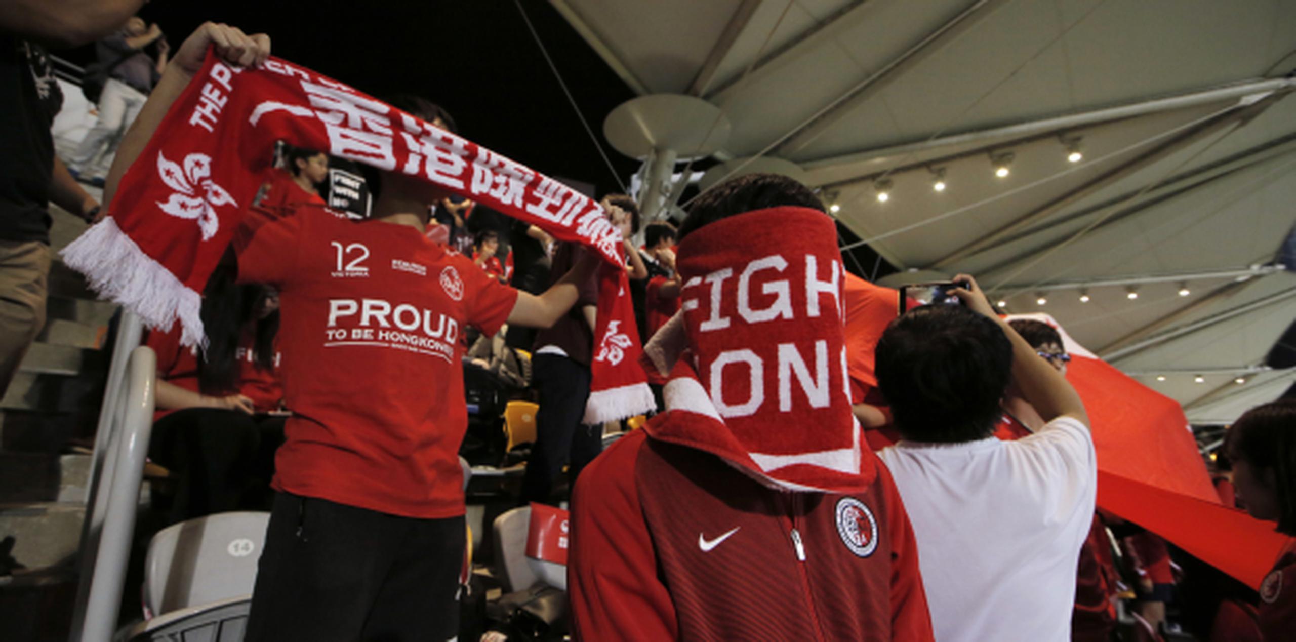Seguidores del equipo hongkonés se cubren el rostro mientras abuchean el himno de China antes del inicio del partido amistoso entre Hong Kong y Bahréin. (AP/Kin Cheung)
