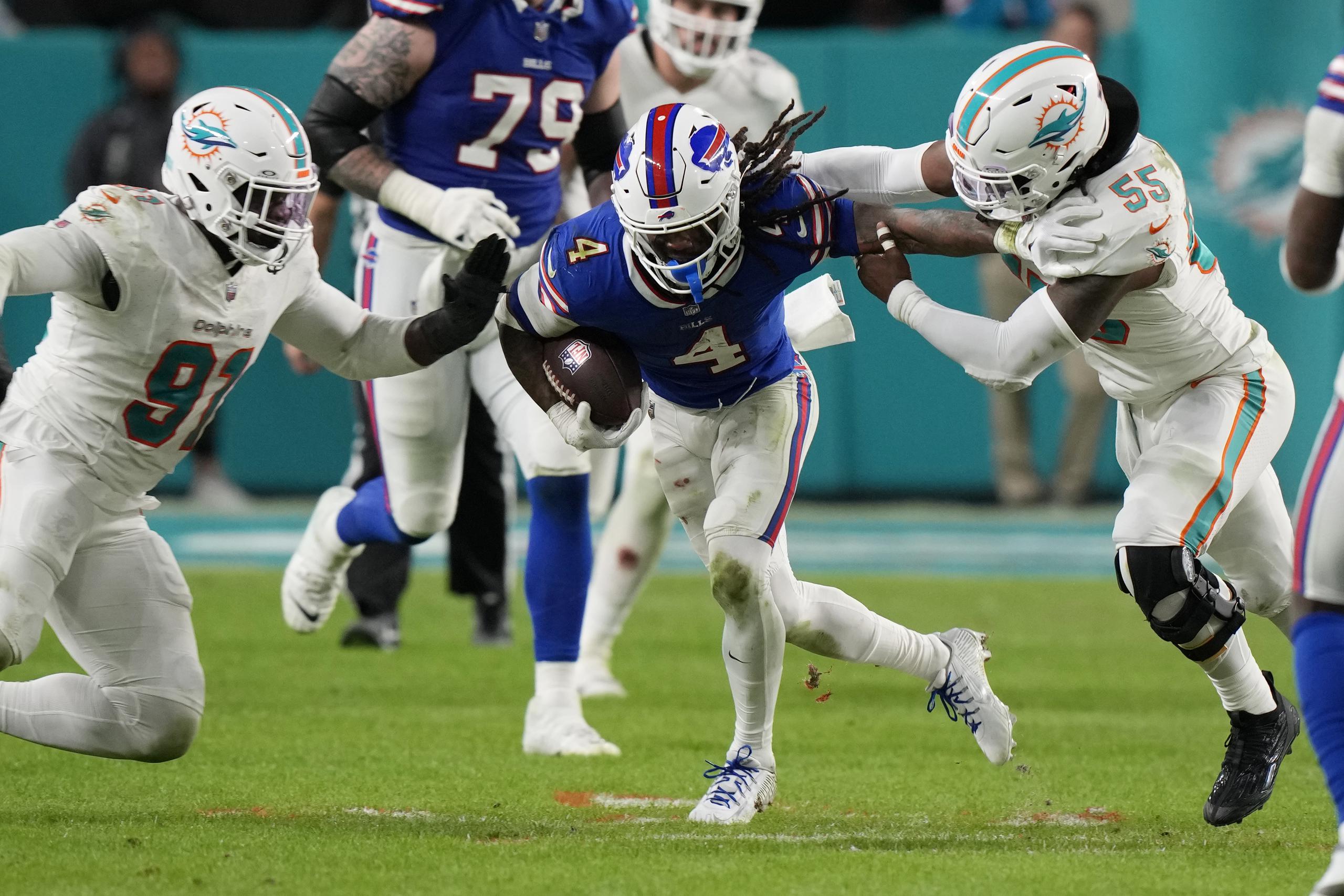 El defensive end de los Dolphins de Miami, Emmanuel Ogbah, y el linebacker Jerome Baker intentan derribar al corredor de los Bills de Búfalo James Cook en el encuentro del domingo.