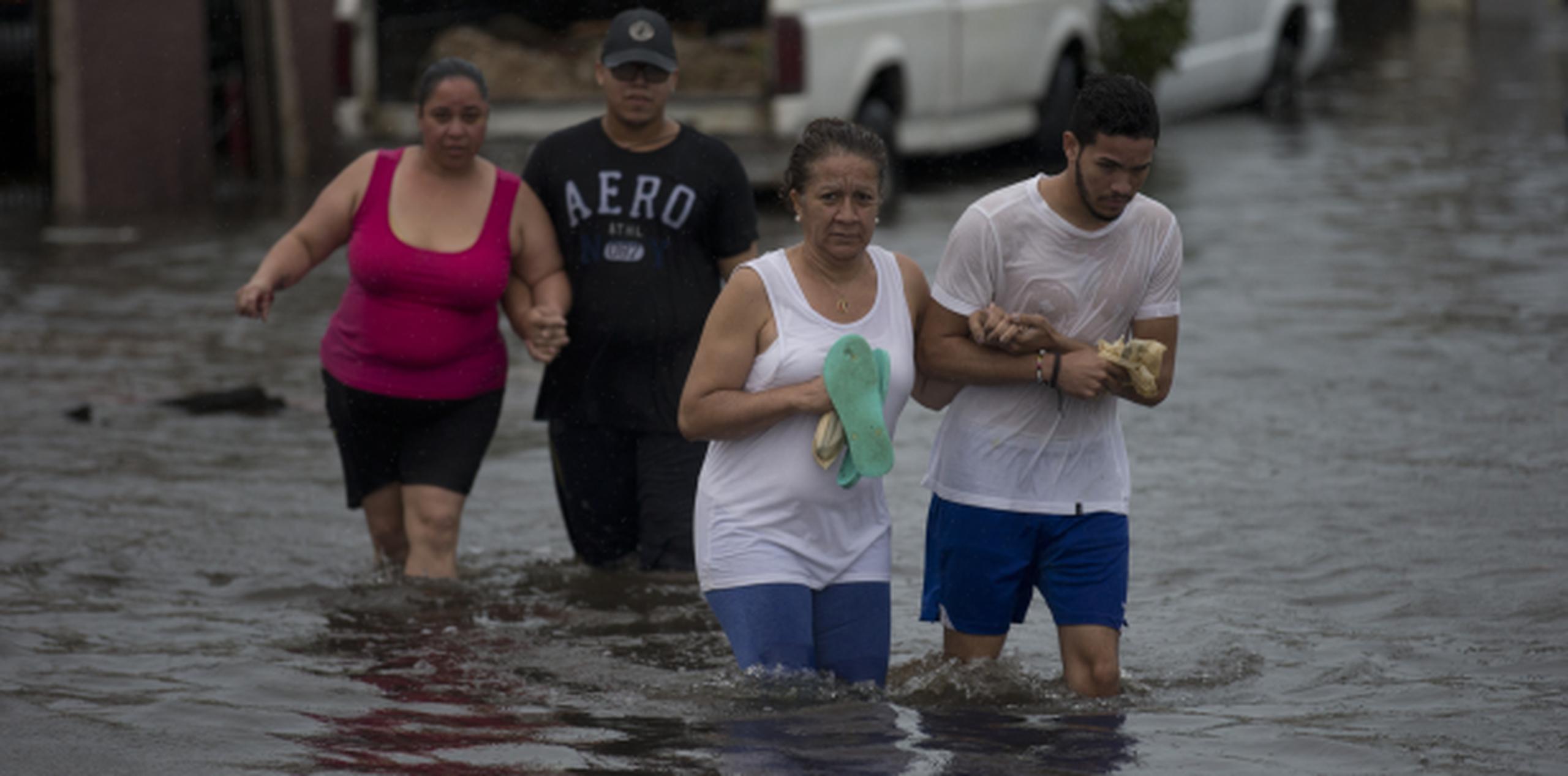 En el sector Juana Matos, en Cataño, se estima que se perdieron 457 casas. En la foto, vecinos buscan un lugar seguro en medio de las inundaciones. (teresa.canino@gfrmedia.com)