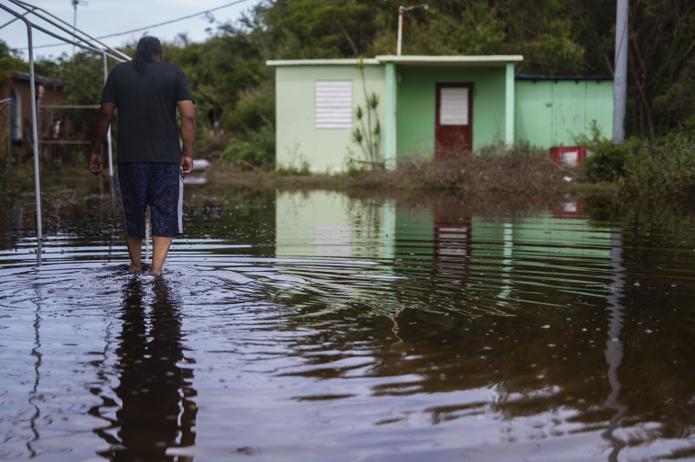 Un residente del barrio Pozuelo de Guayama camina por la inundación causada por el huracán Fiona.